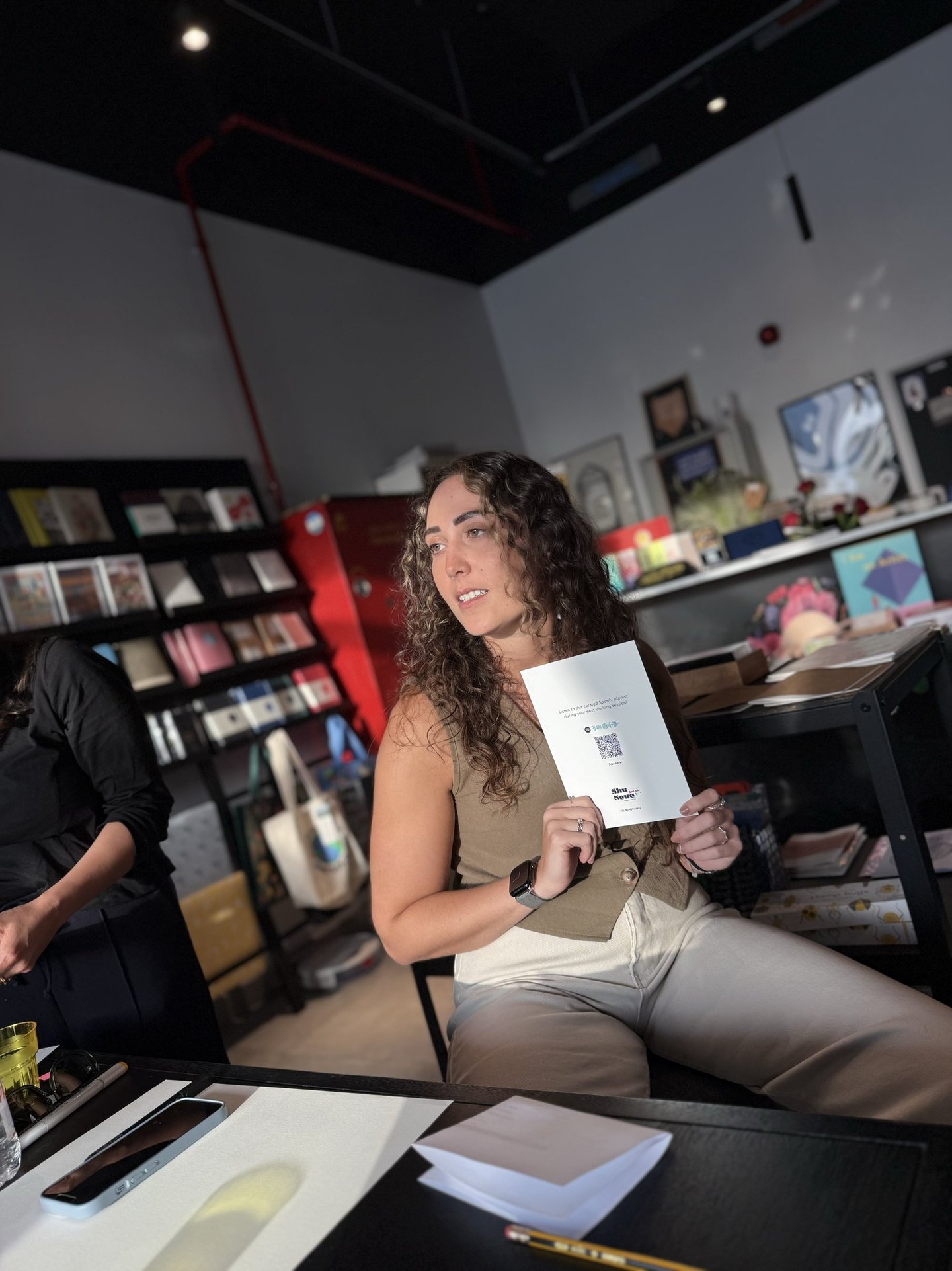 Judy sits in a bookstore holding up a designed card