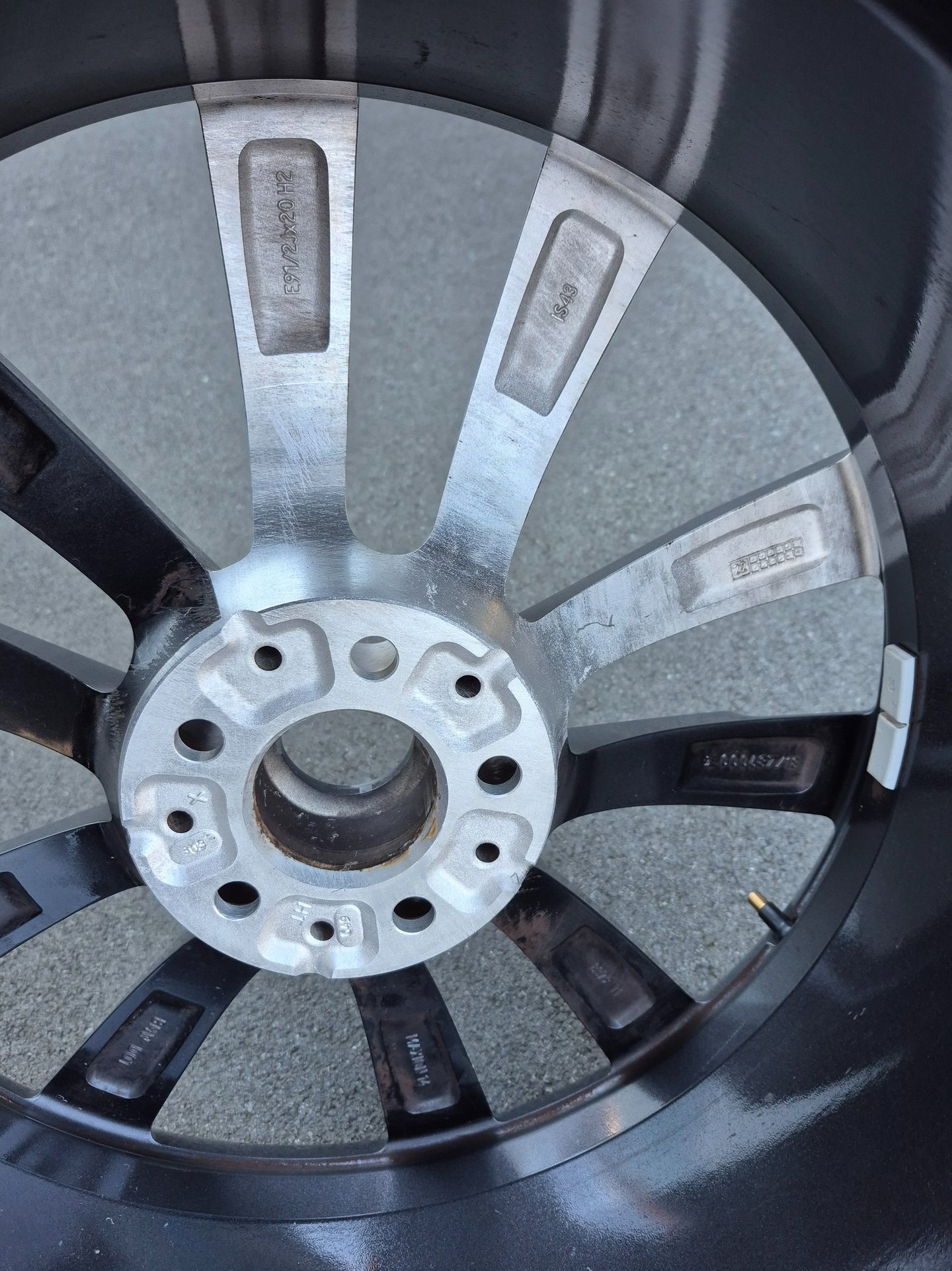 Inner view of a multi-spoke alloy car wheel rim showing the hub assembly and stamped serial numbers.
