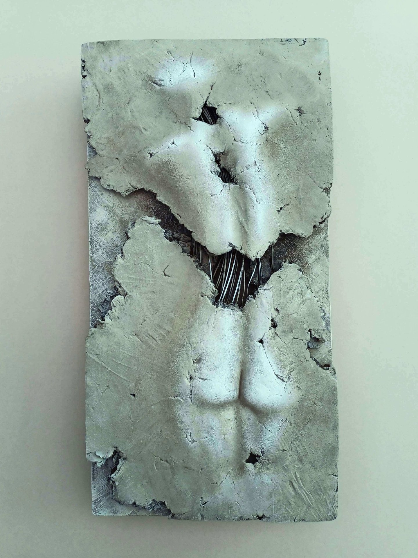A relief sculpture of a fragmented female (rear view) showing exposed wires, painted cool browns