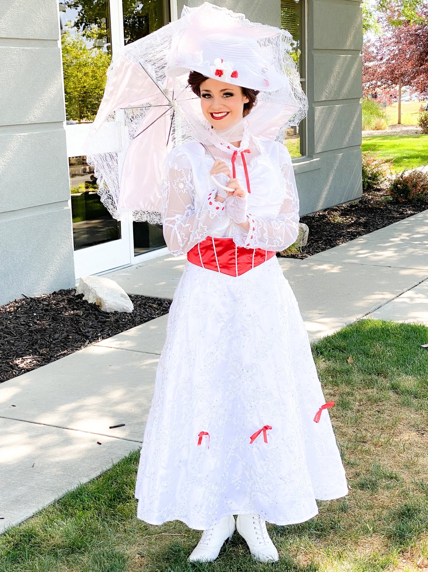 Beautiful performer in a jolly holiday white lace dress holding a parasol.