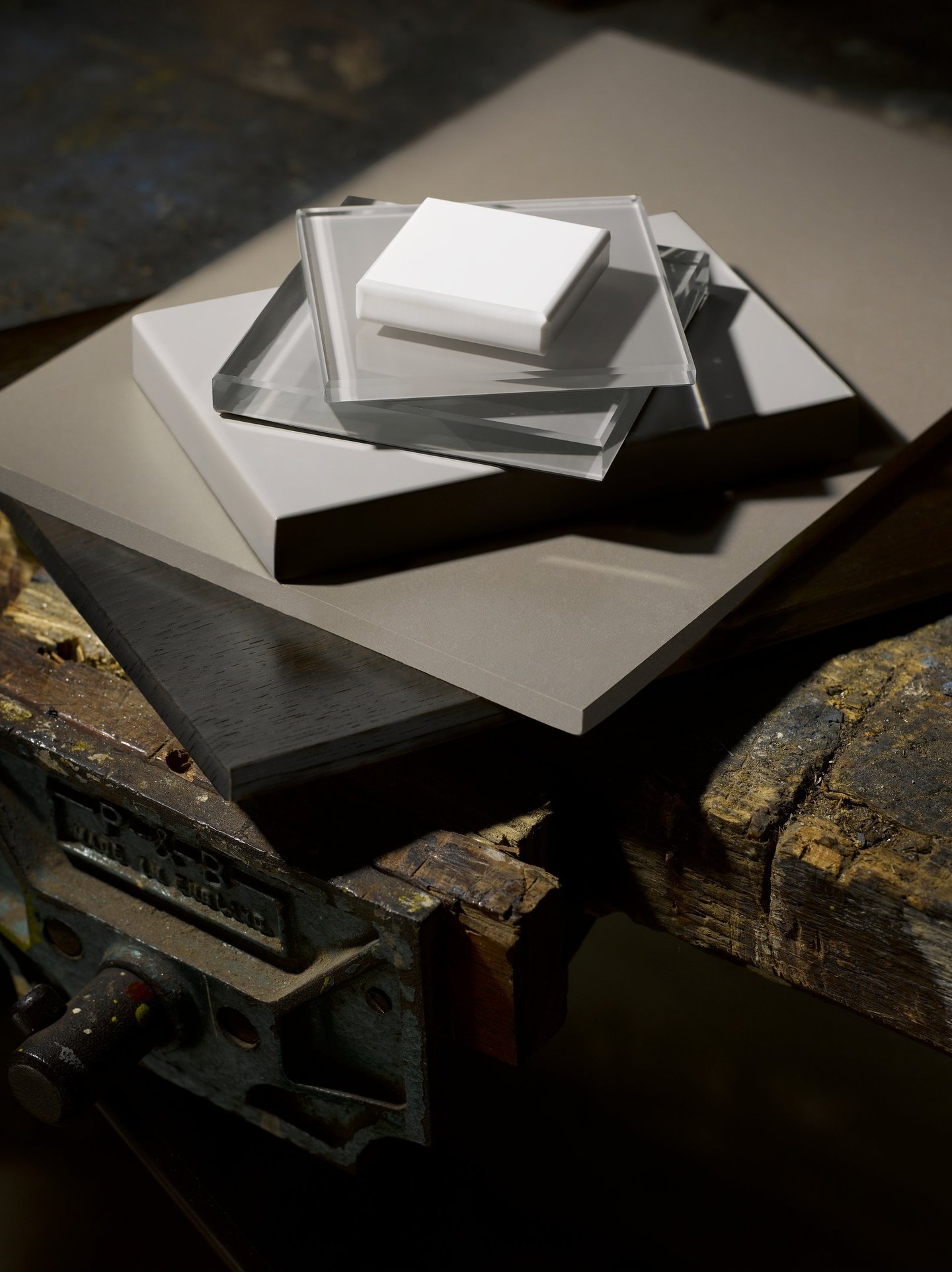 pieces of tile slate and glass stacked on top of an old wooden workbench and vice