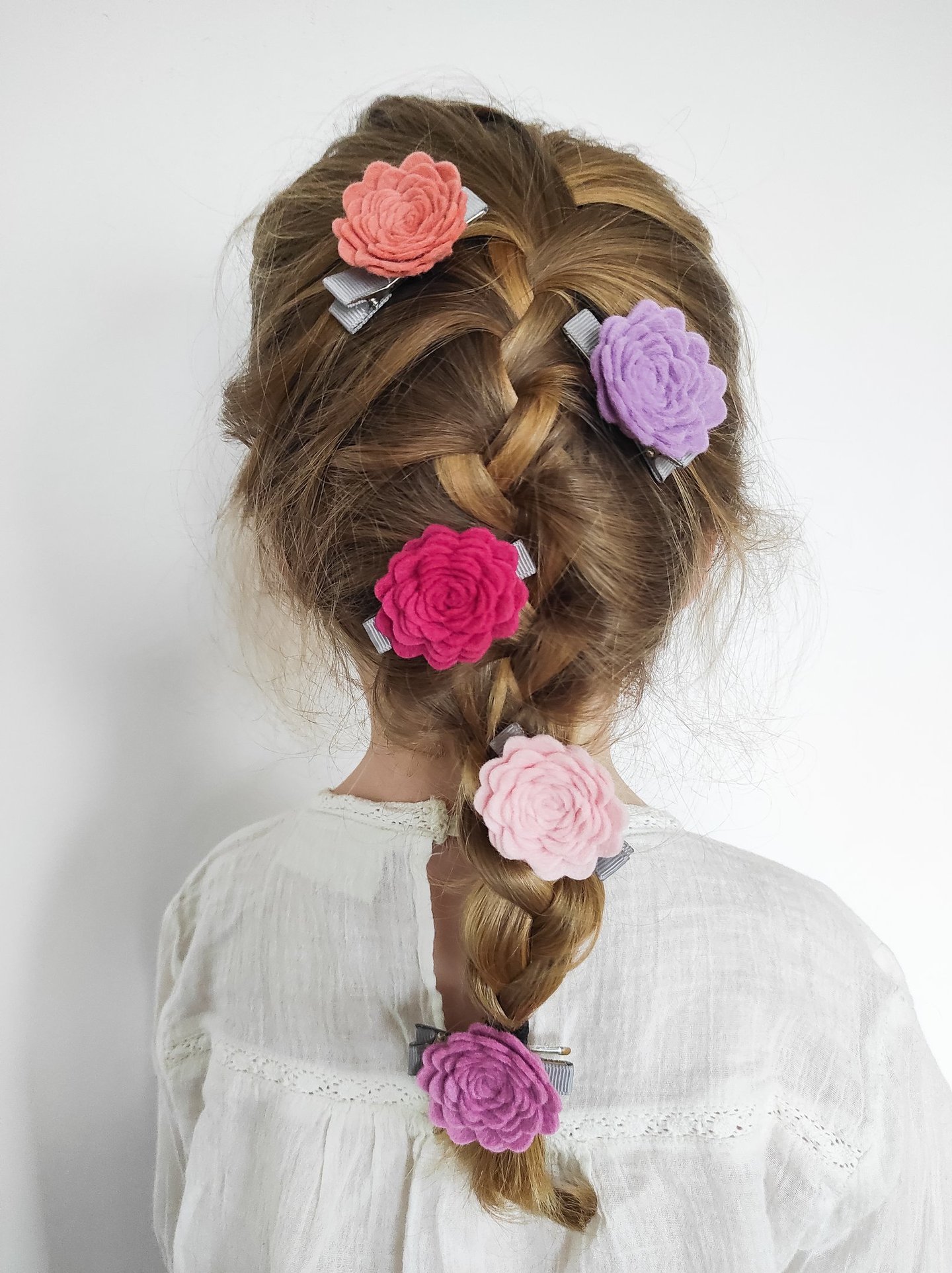 dziewczynka z warkoczem, w który wpięte są spinki w kształcie róż