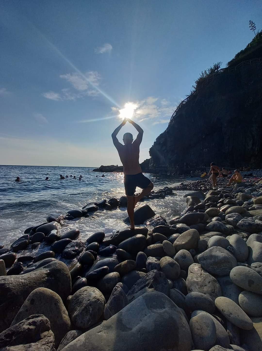 a man performing yoga on rocks in the sea