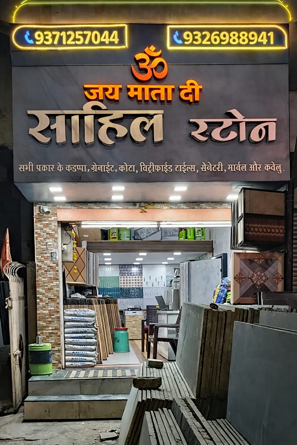Sahil Stone shop front displaying granite, tiles, and sanitary ware at night with illuminated signage.