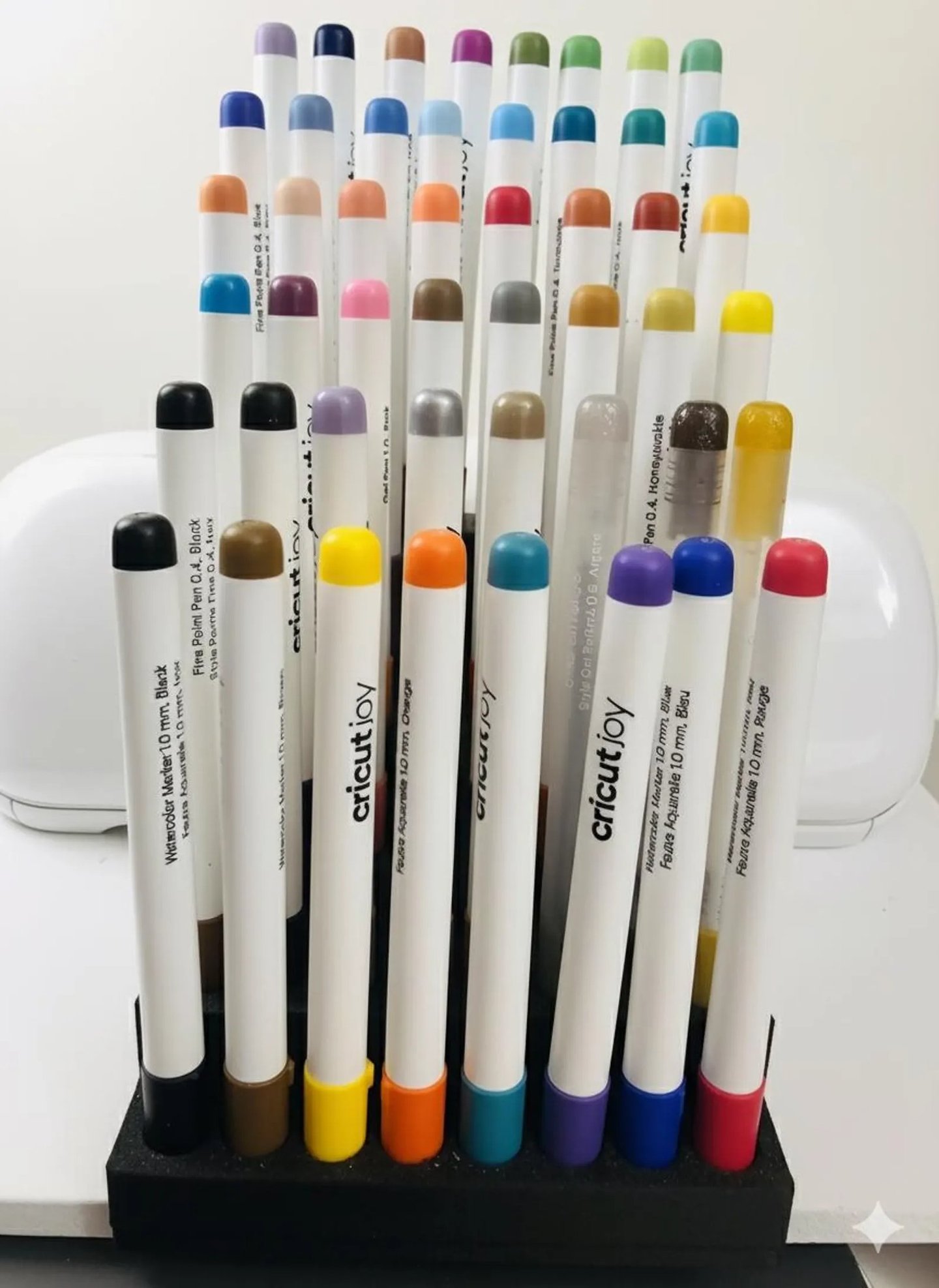 A collection of colorful Cricut Joy watercolor markers and fine point pens in a vertical storage organizer.