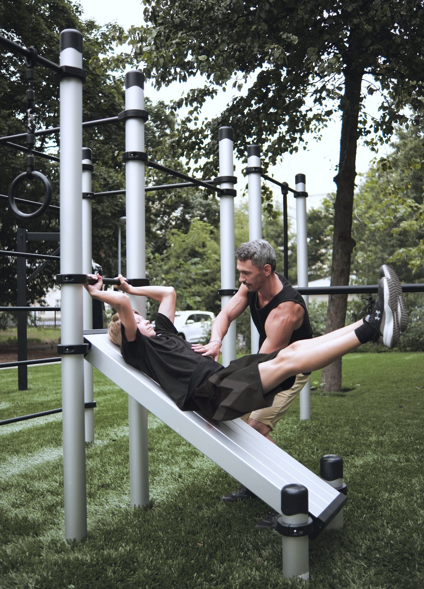 Enfant s’entraînant sur un équipement Kenguru Pro Kids Workout avec l’aide d’un coach.
