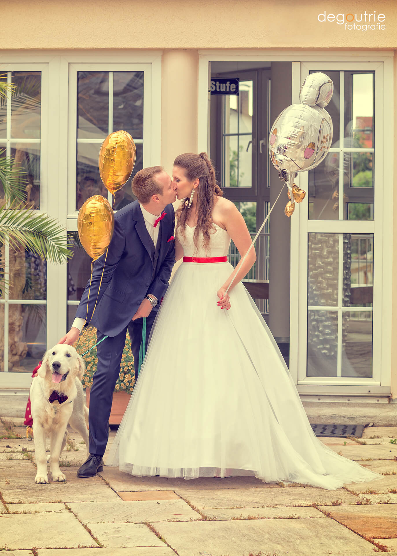Küssendes Brautpaar mit Ballons und Hund mit Fliege
