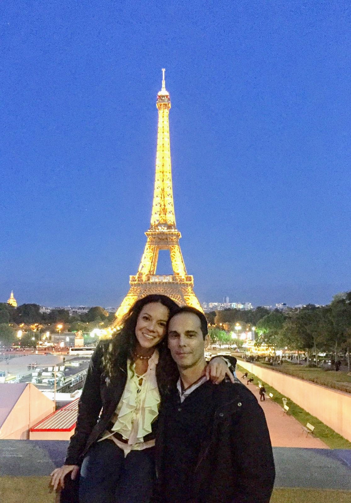 Couple standing in front of illuminated Eiffel Tower at night in Paris France