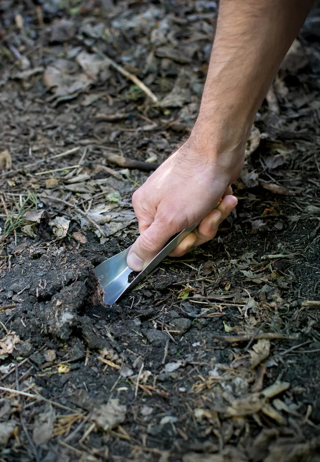 hand pushing backwards on bogerlco trowel to dig up soil