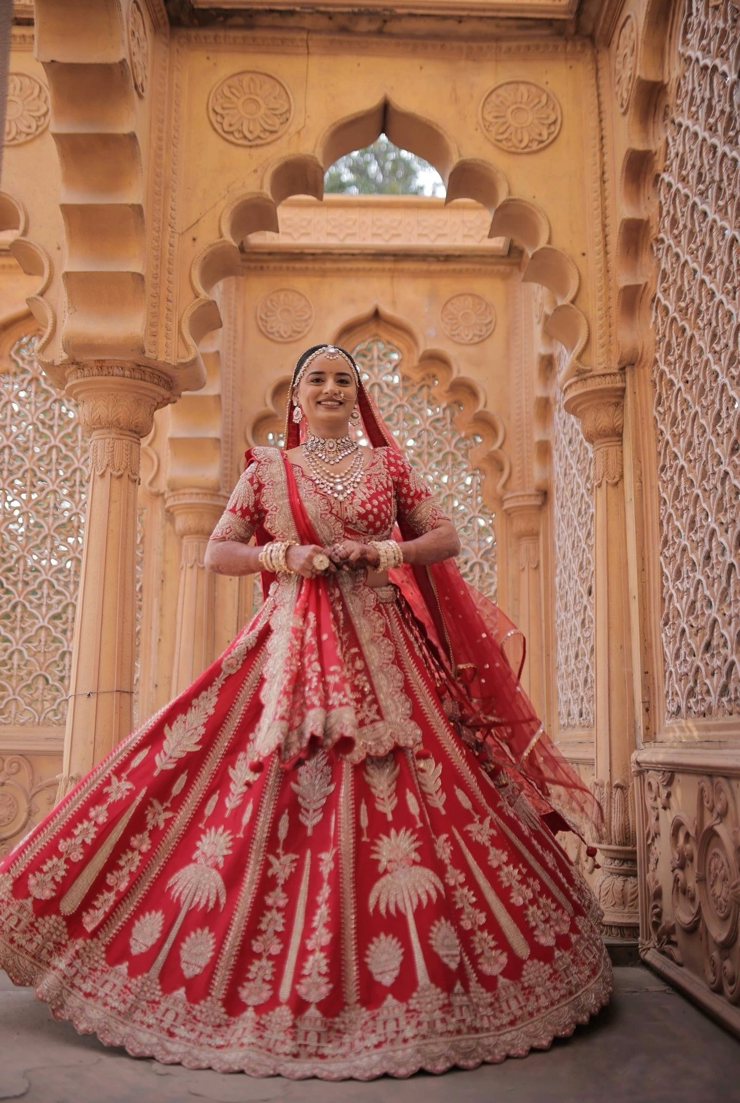 Full length red bridal lehenga with professional wedding makeup in Vadodara