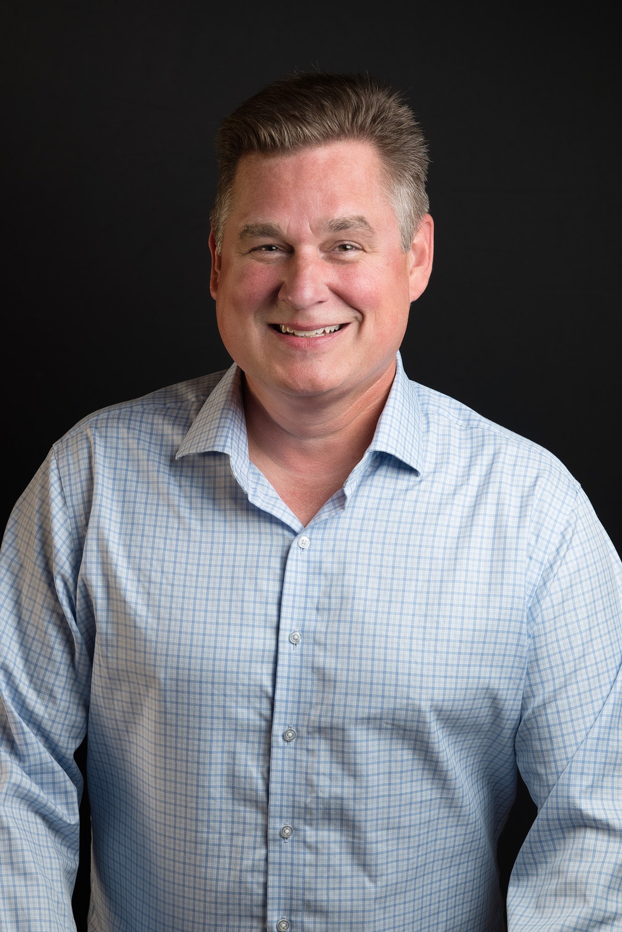 a man in a blue shirt and a white shirt smiling