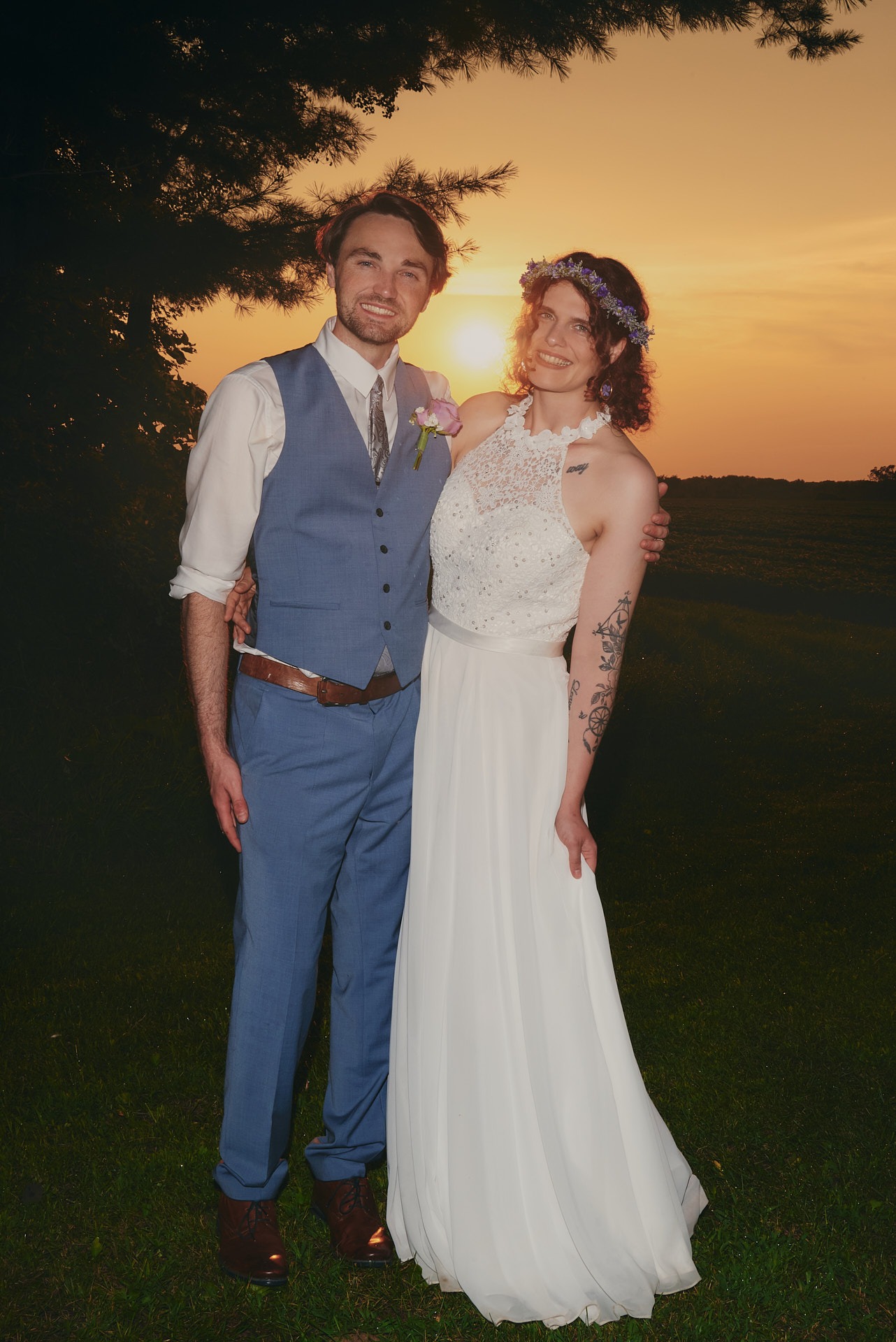 a bride and a groom standing in front of a sunset