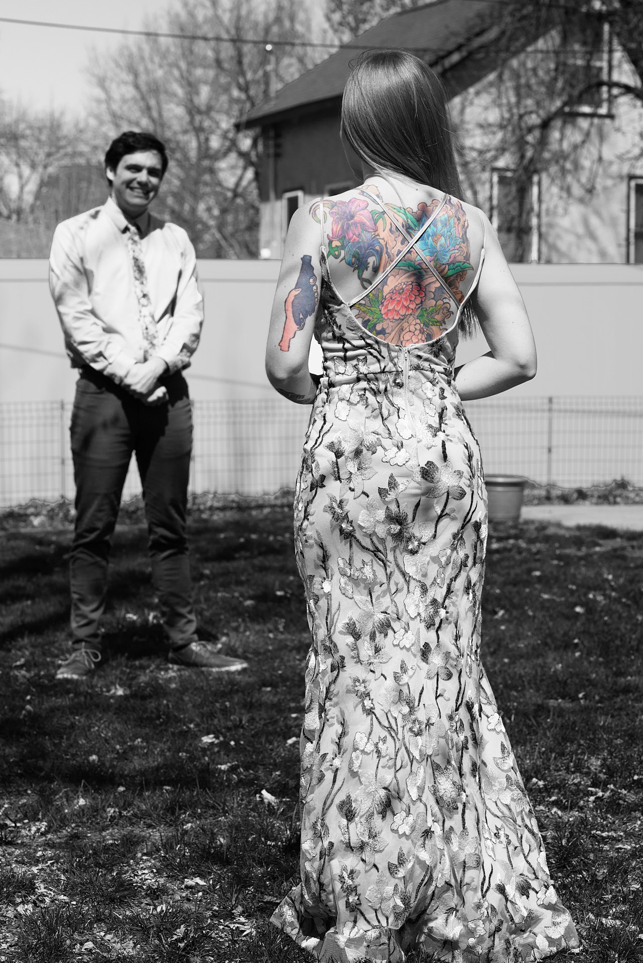 a woman with tattoos on her back looking at a man in front of her