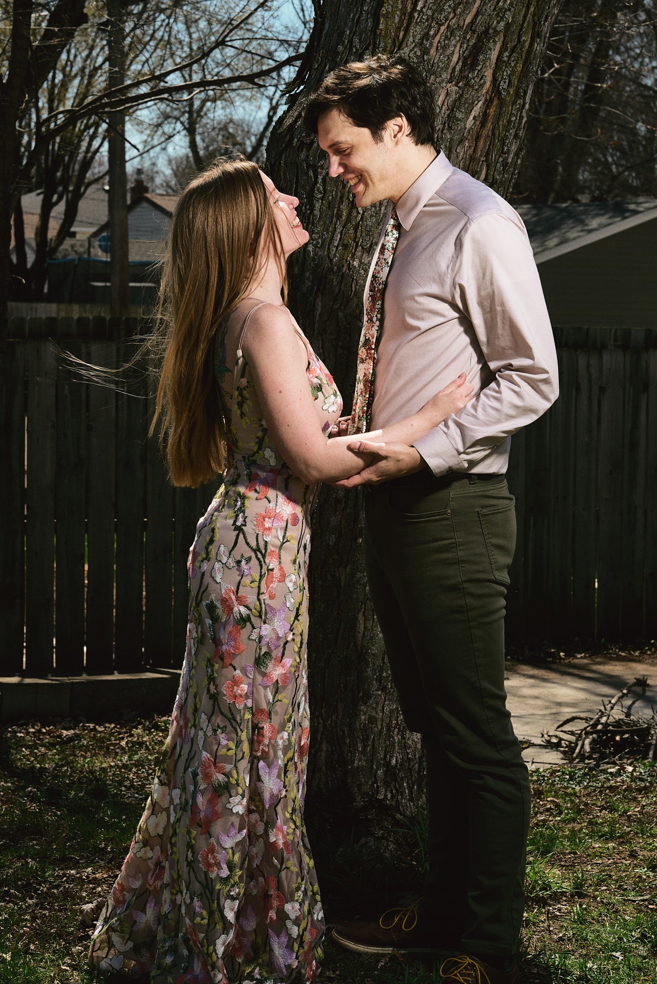 a man and woman facing each other and standing in front of a tree