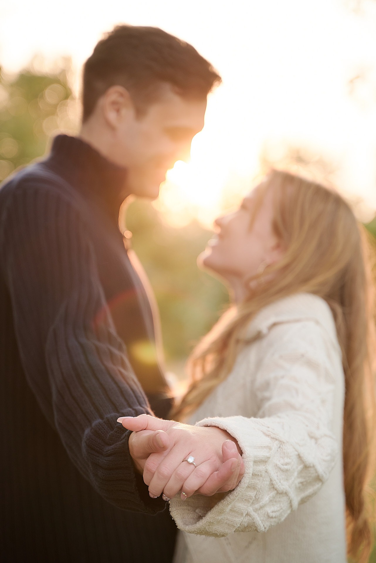 a man and woman holding hands and looking at each other showing the engagement ring in the front