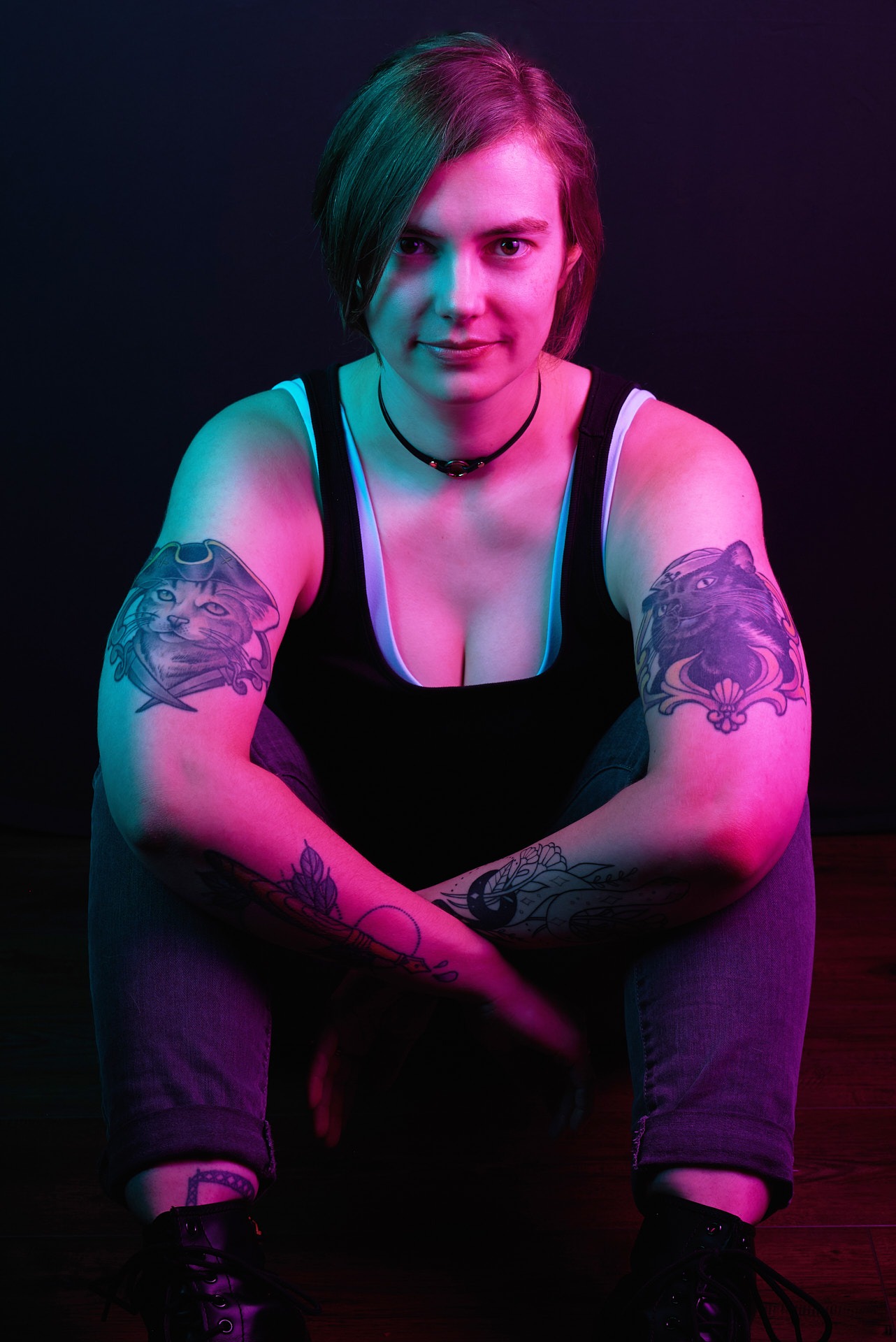 a woman with cat tattoos on her both arms with pink lighting on her skin