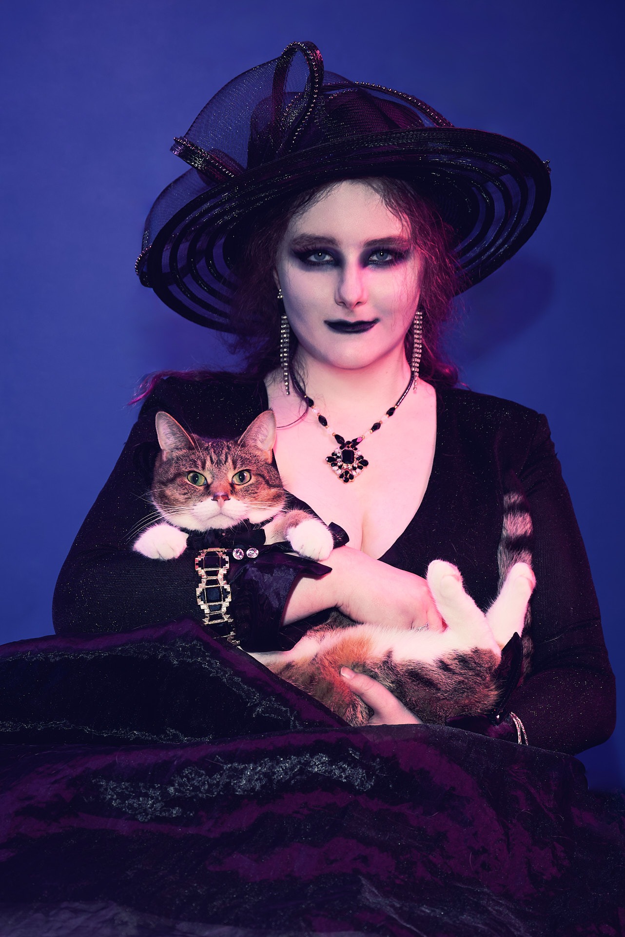 a woman in a witch costume wearing a black hat and holding a cat