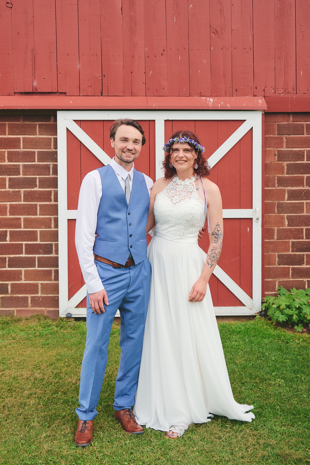 a bride and a groom standing in front of a barn