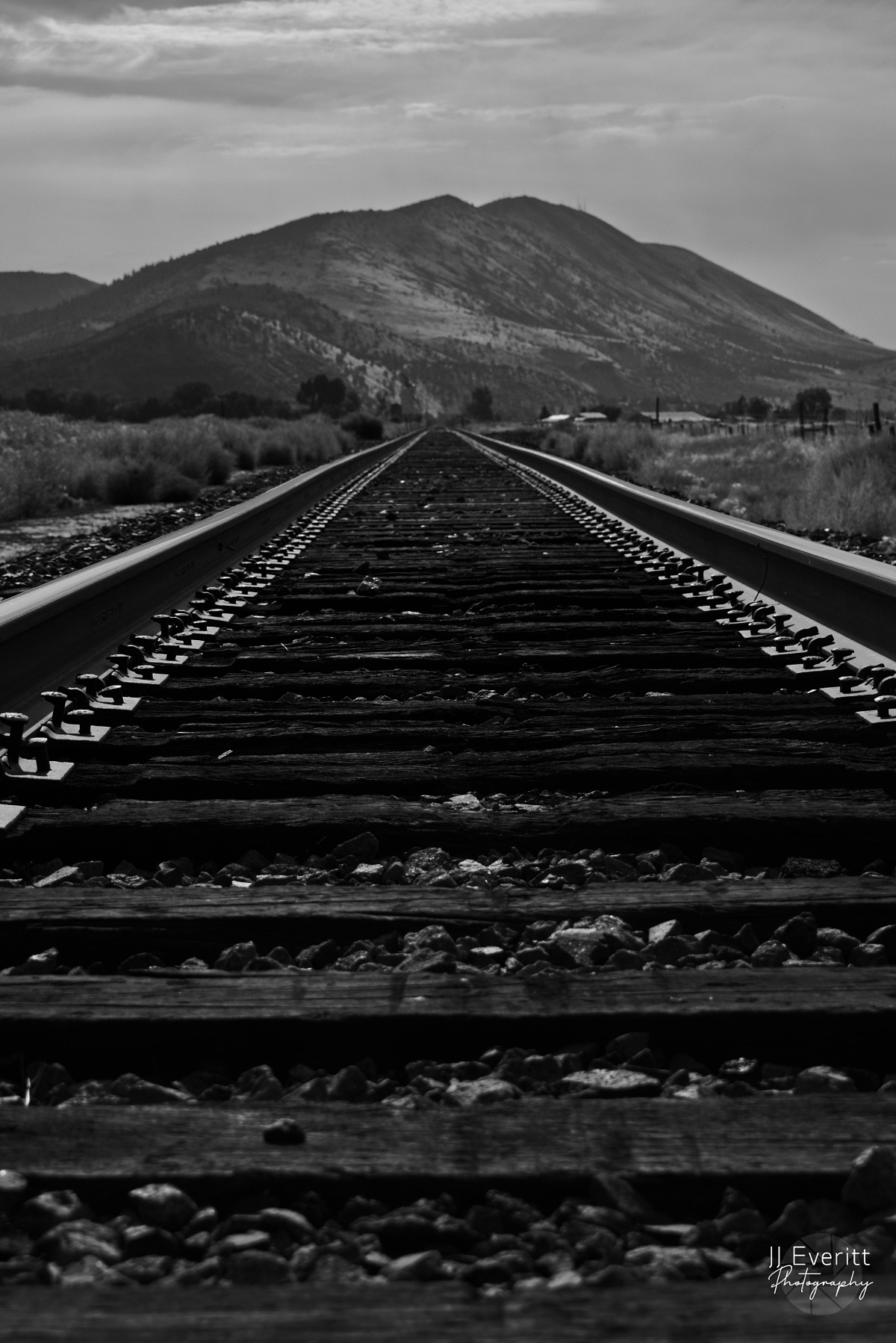 a train track with a mountain in the background taken by Jordan Boyle of JJ Everitt Photography