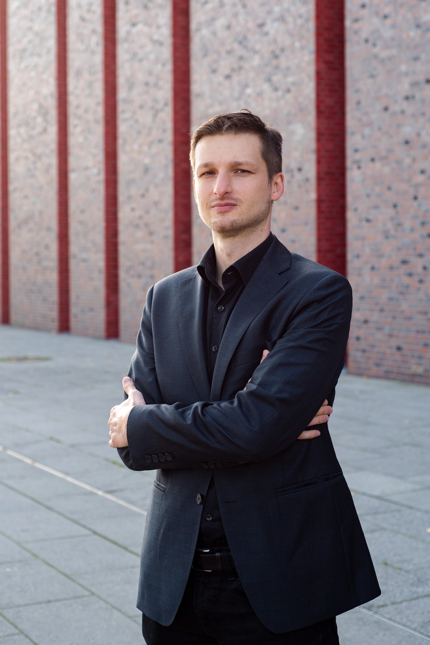 a man in a suit and tie standing in front of a brick wall
