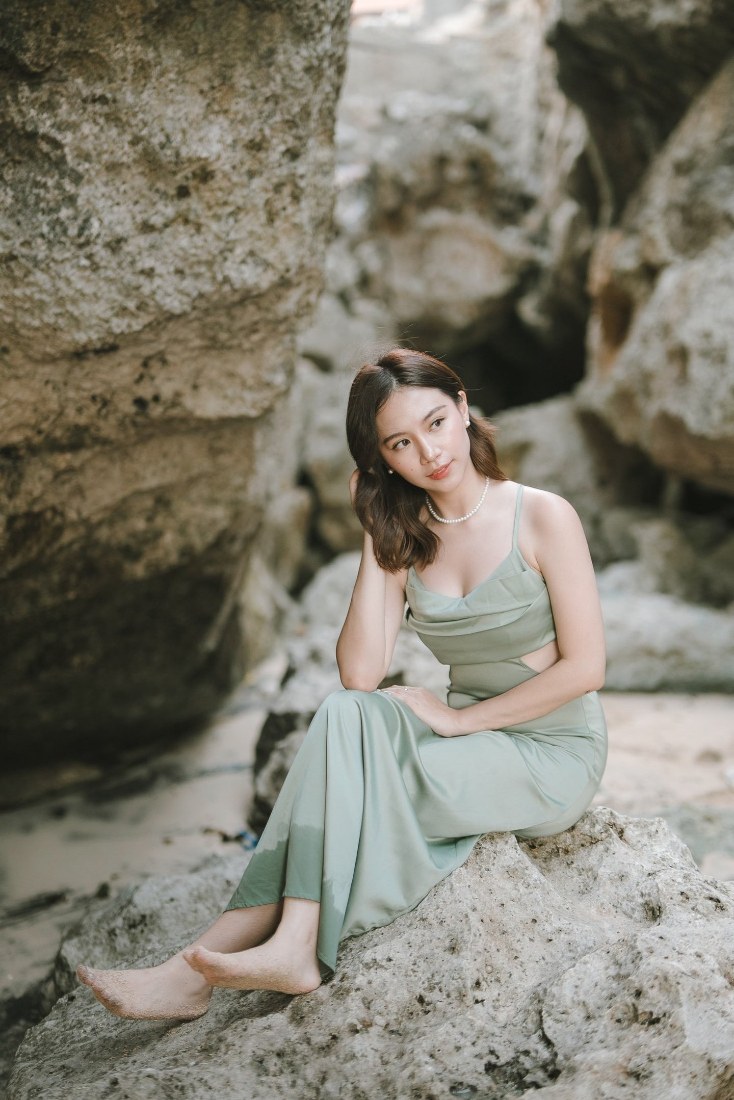 Portrait of woman sitting near rock formation during photoshoot at Geger Beach Nusa Dua Bali
