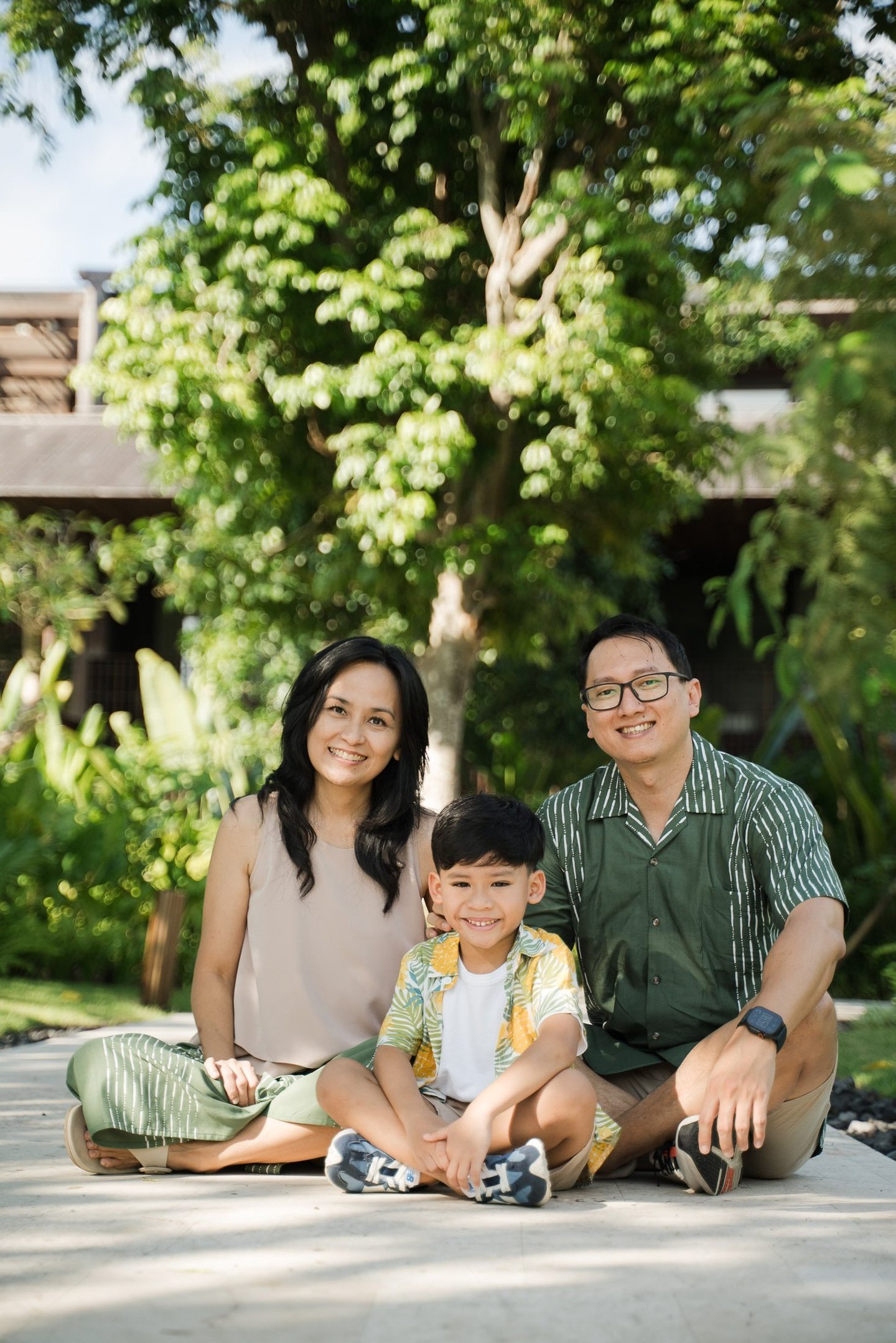 Family sitting together on garden pathway during a relaxed family photography session at The Meru Sanur Bali
