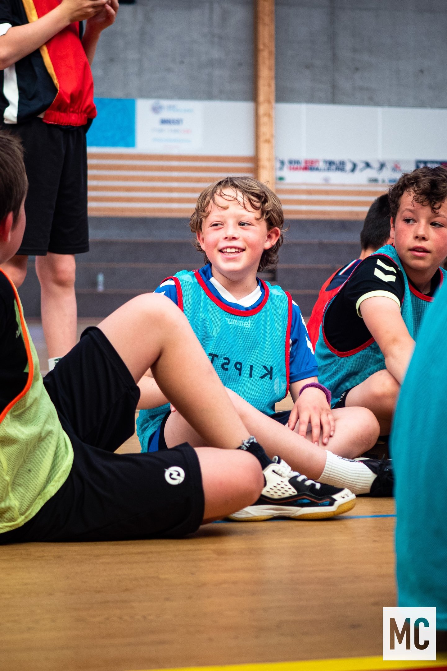 a group of young boys sitting on a basketball court