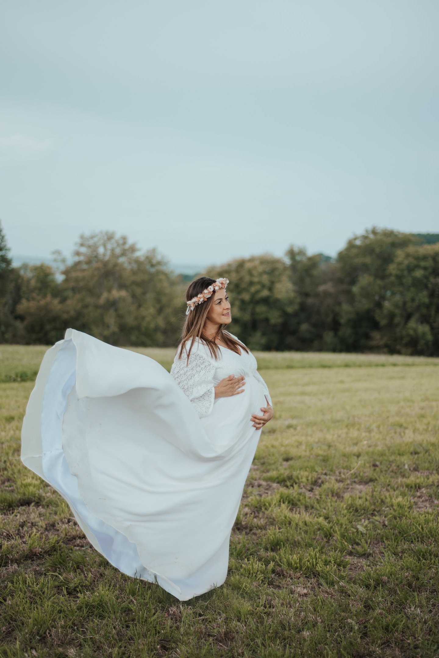 a pregnant woman in a white dress with a flower crown