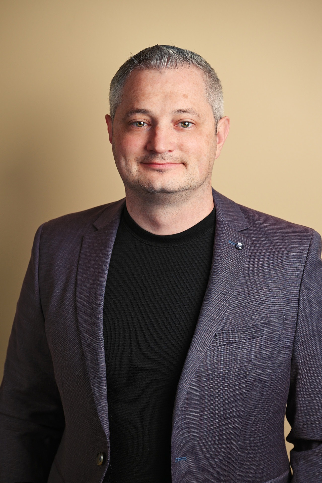 a man in a suit and black shirt with indoor lighting