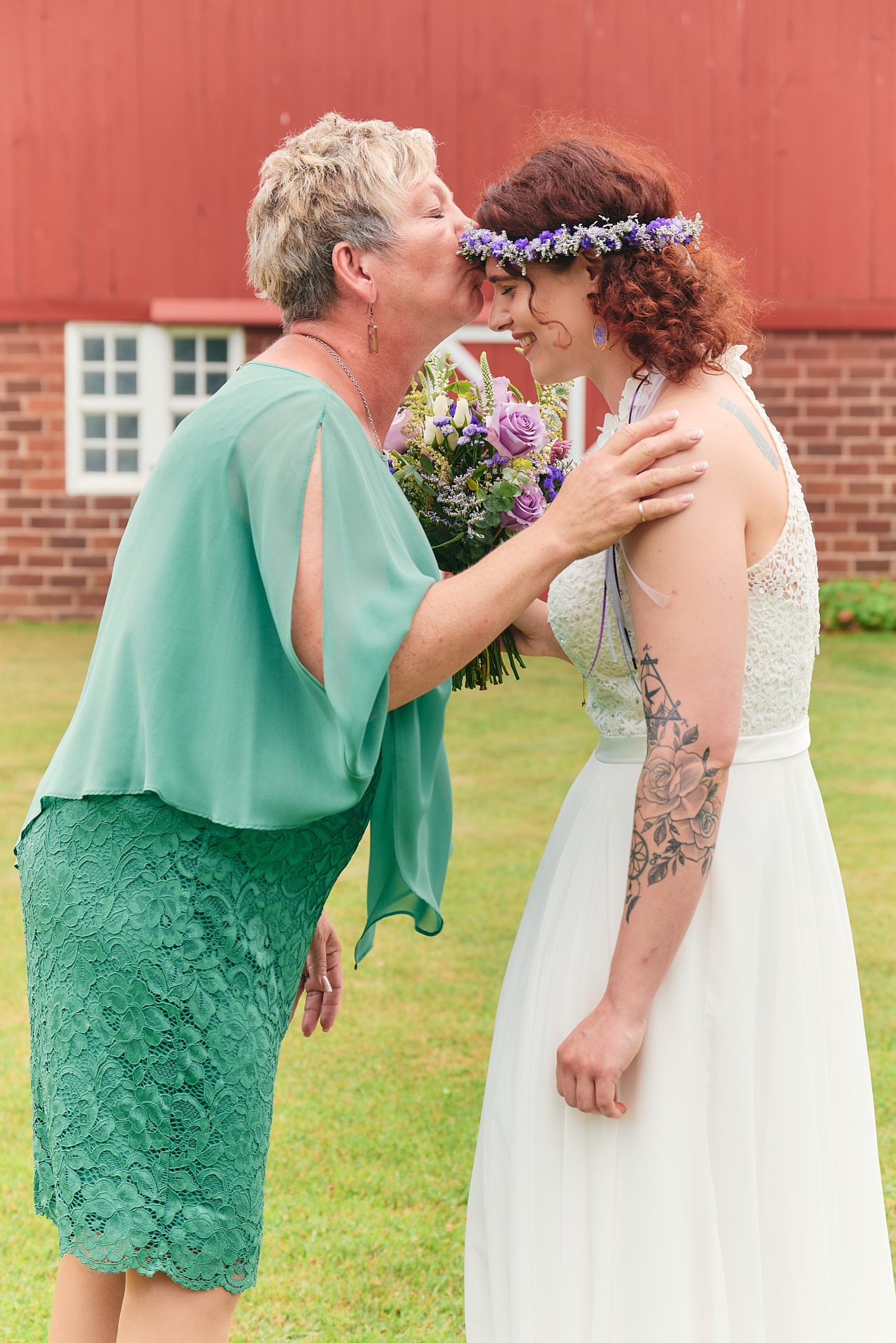 a woman in a wedding dress is kissed by her mother