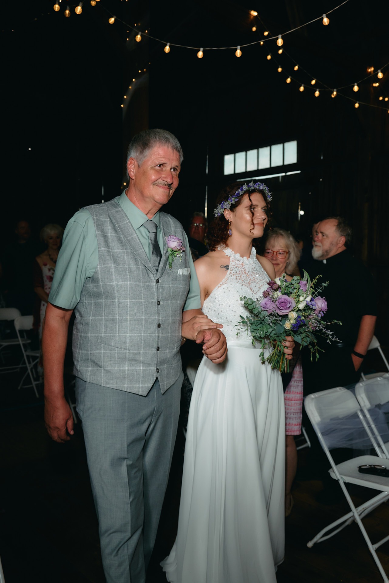 A father and a bride walking down a aisle in a barn wedding