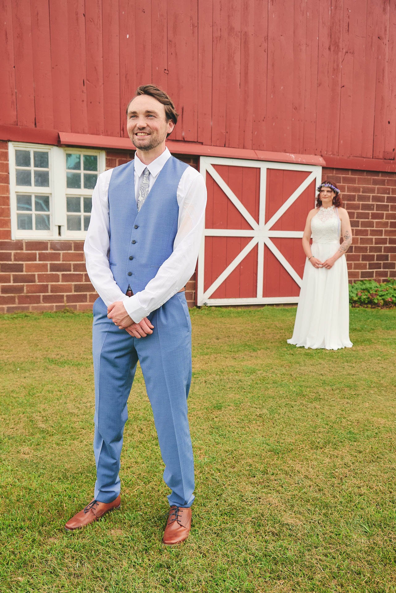 a man in a blue vest and suit and a woman in a white dress behind him