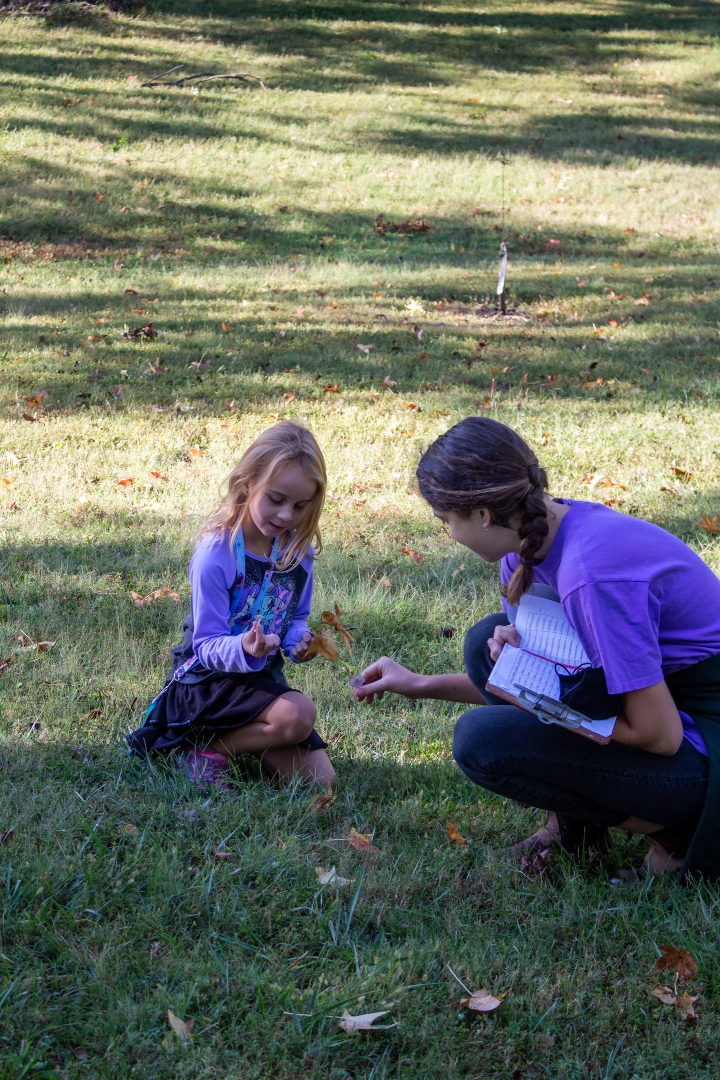 Teacher with one of our youth students outside, picking up natural pieces for an art project.