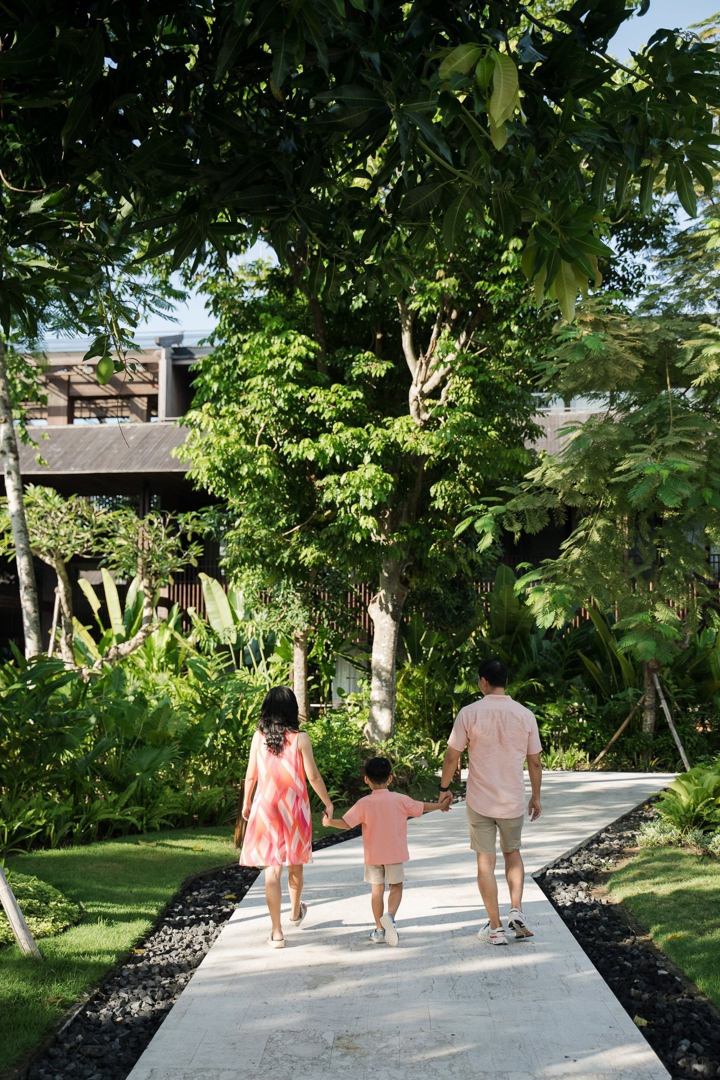 Parents holding their child while walking through tropical garden at The Meru Sanur Bali family photography
