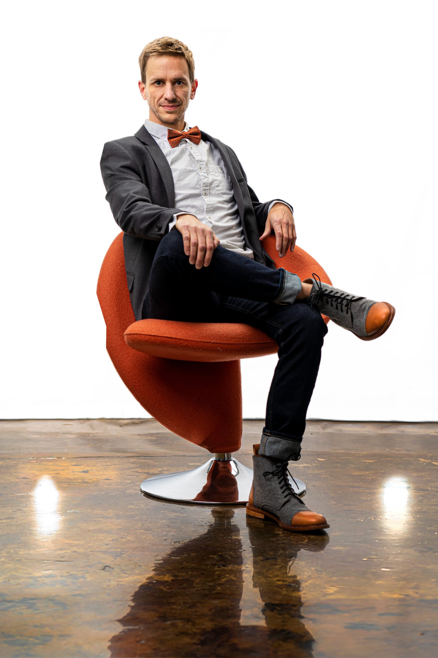 Remy sits in a chair wearing a sportcoat and bowtie