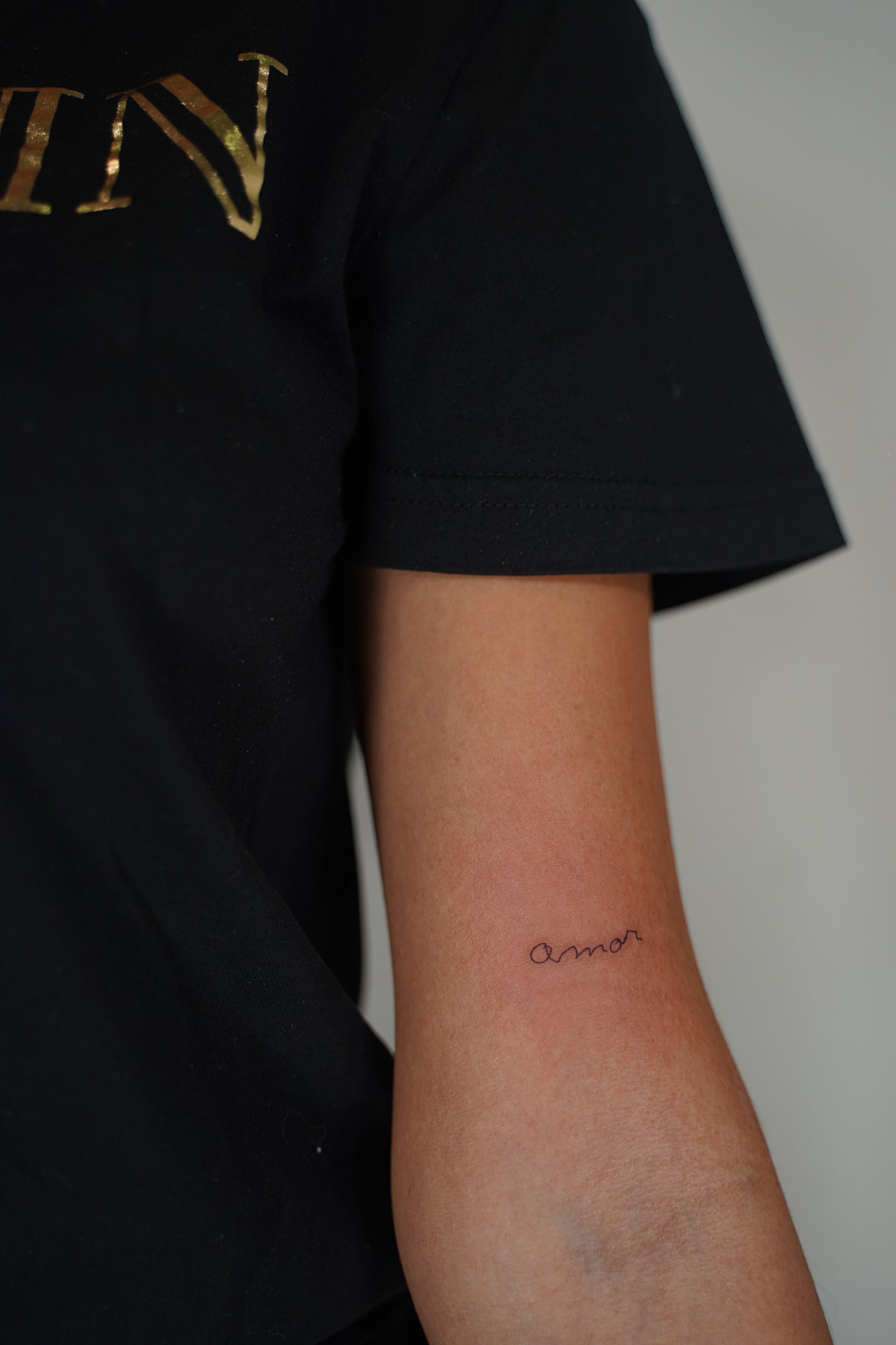 Tatuaje fineline en Madrid con lettering amor en cursiva minúscula trazo fino en el antebrazo