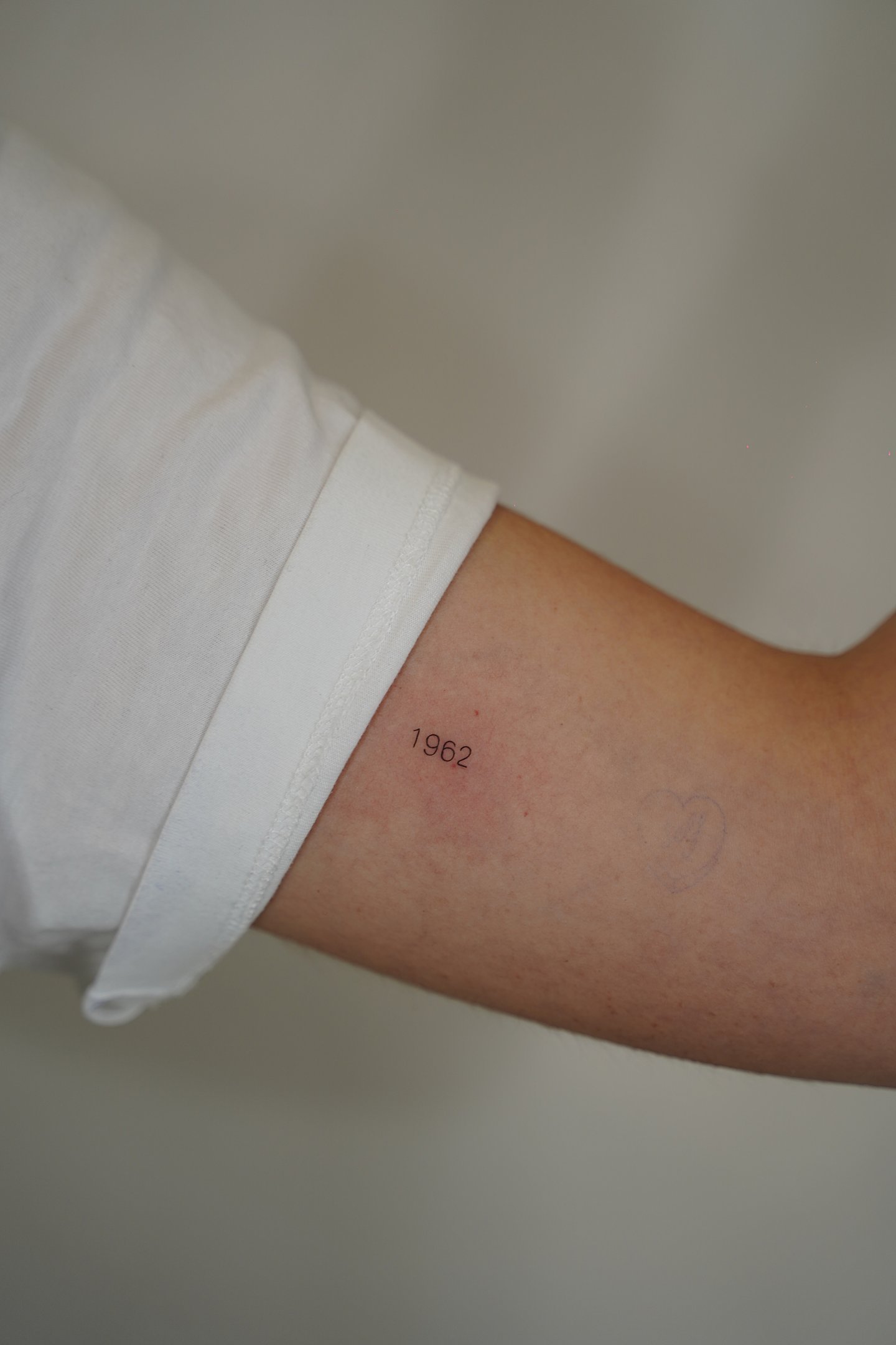 Tatuaje fineline en Madrid de año 1962 en tipografía fina y discreta en el antebrazo