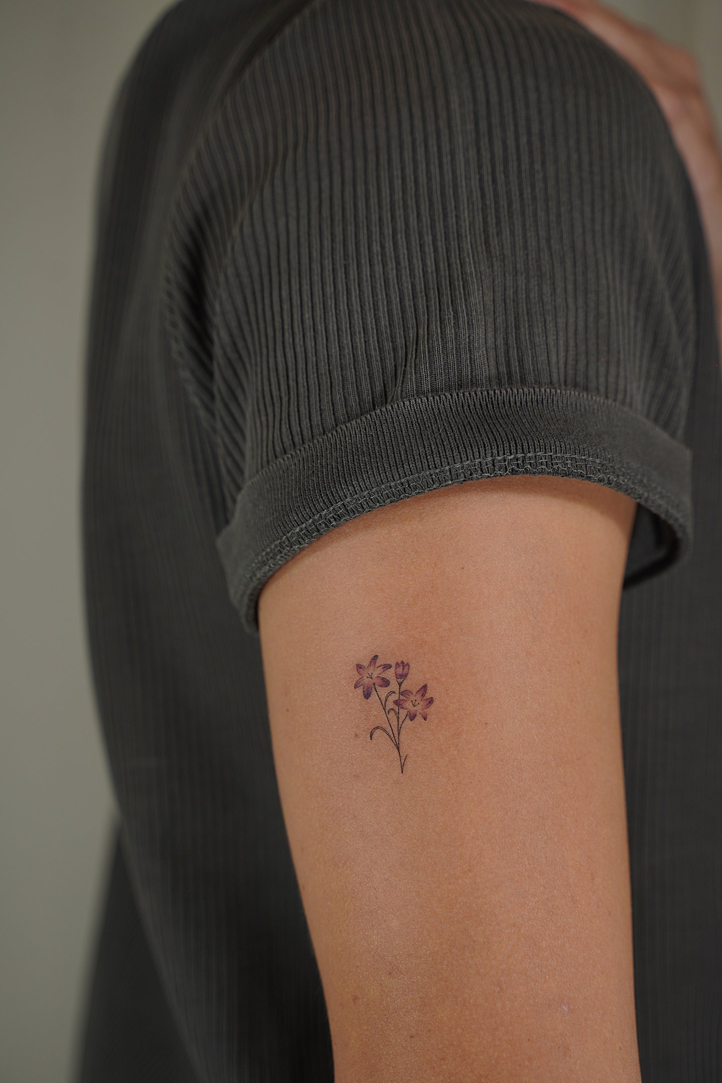 Tatuaje fineline en Madrid de ramo de flores moradas en tinta de color con efecto acuarela en el bra