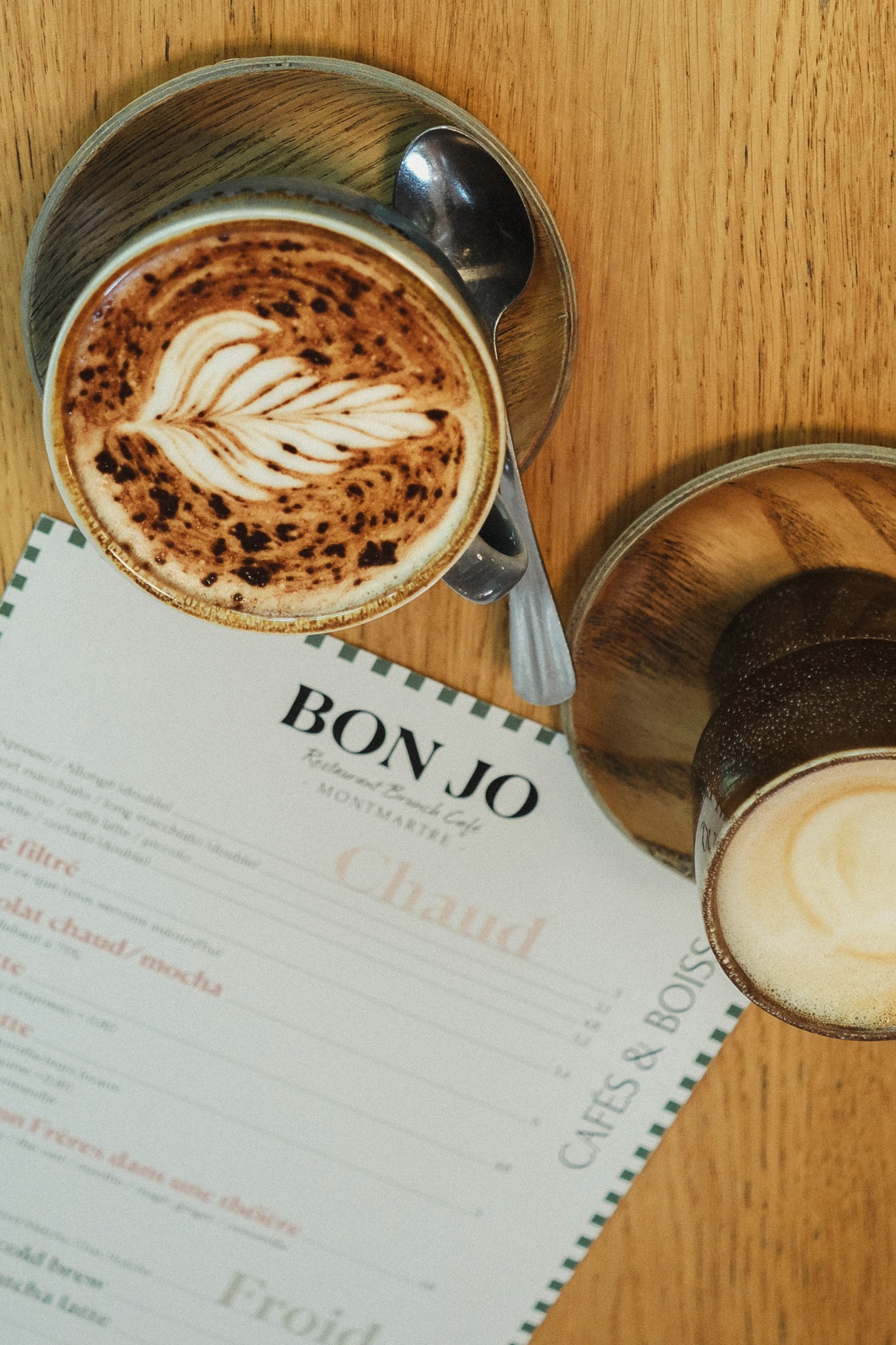 alt="Brunch coffee at Bon Jo café in Montmartre, Paris – artisan latte with menu featuring homemade drinks and breakfast spec