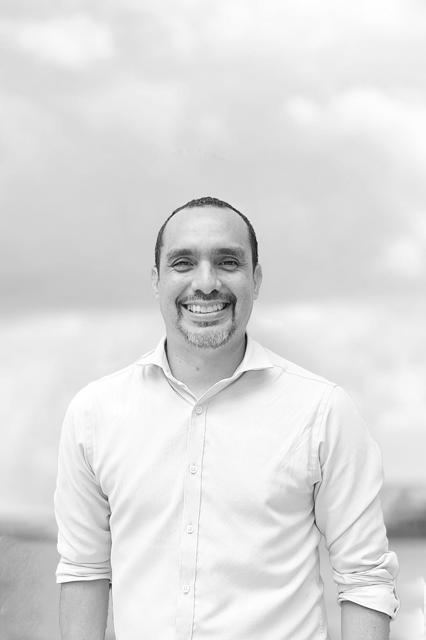 un hombre con camisa blanca sonriendo en foto blanco y negro