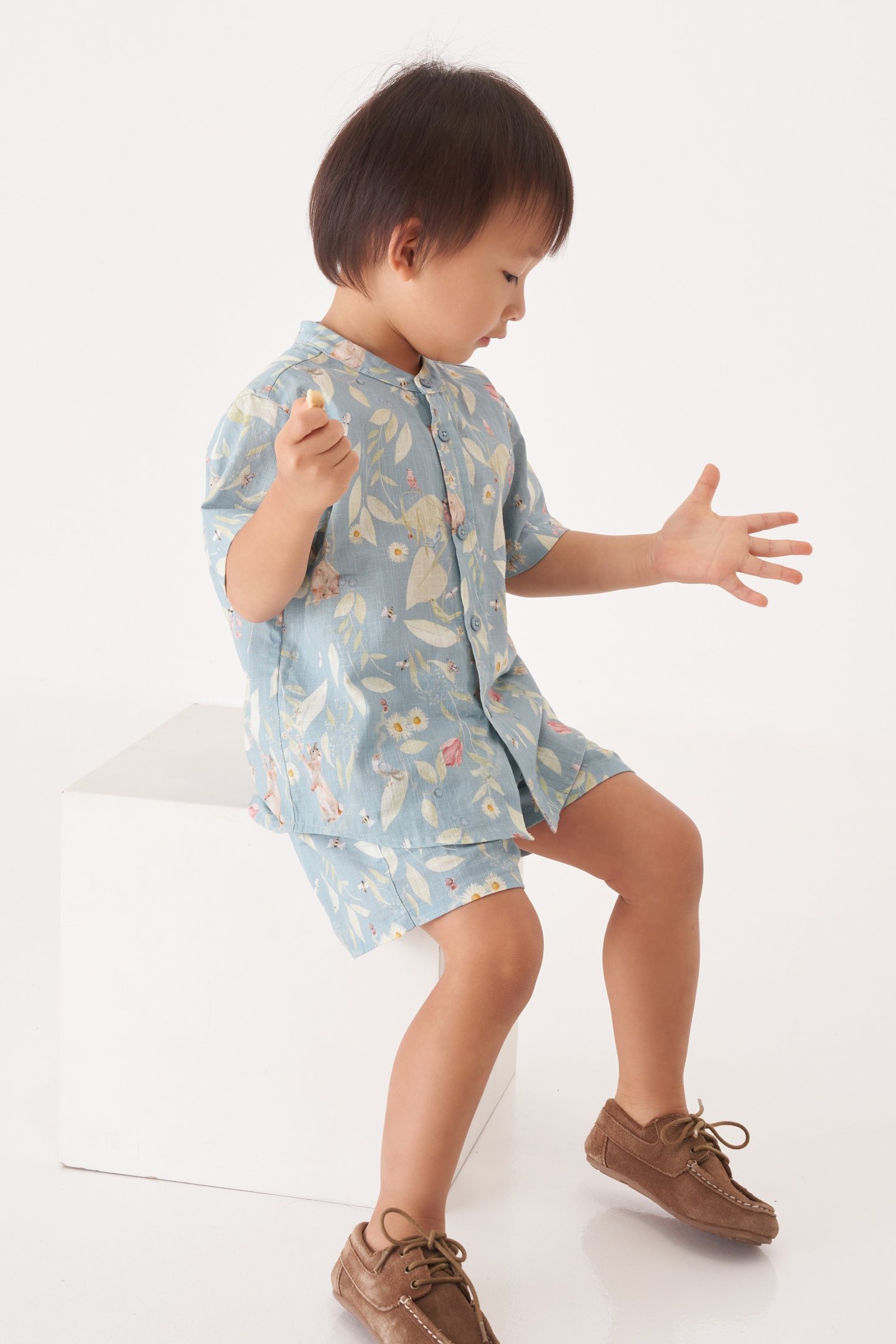 Menino asiático veste roupa com estampa de paisagem natural com animais e plantas