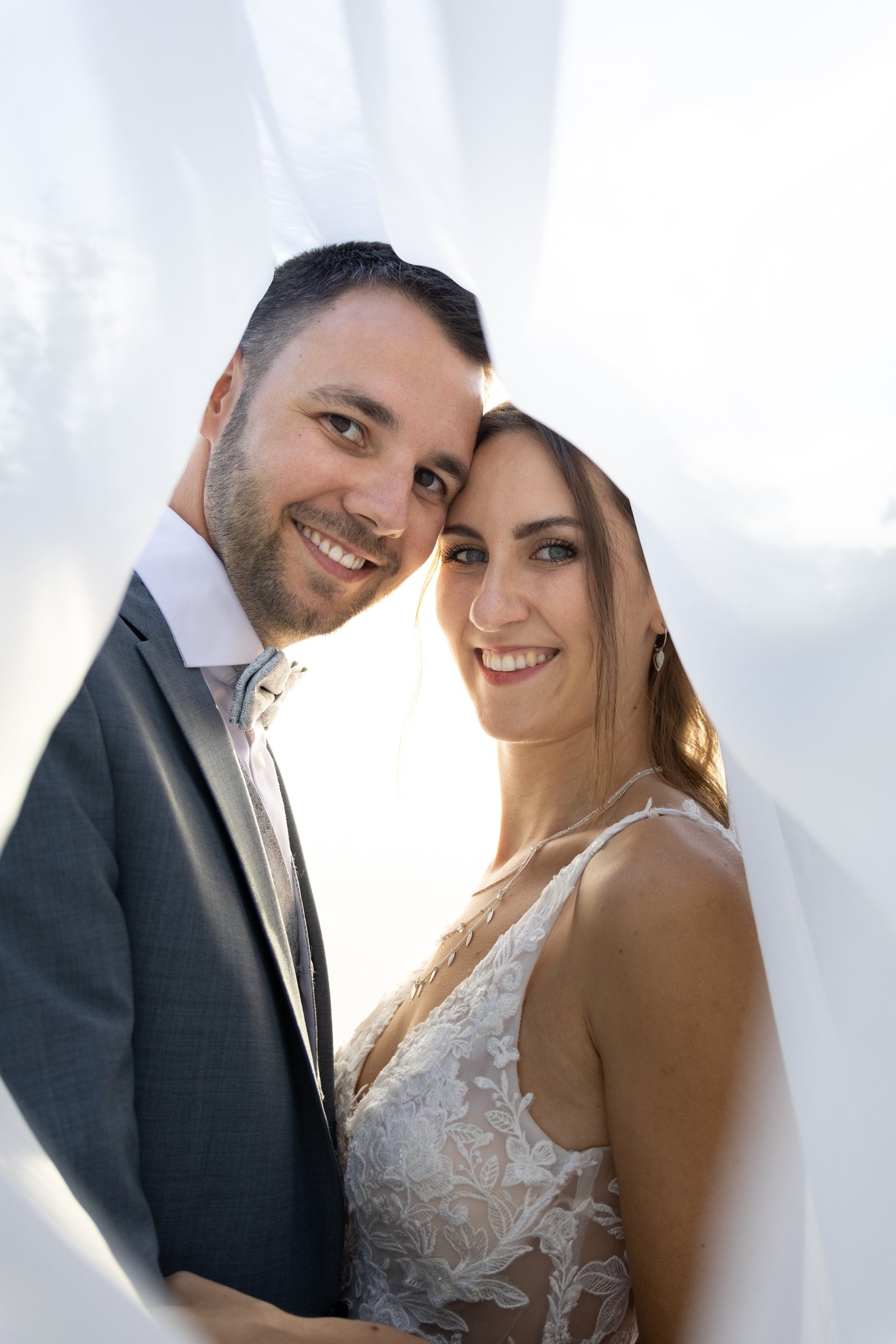 Kreative Hochzeitsfotografie Coburg: Romantisches Brautpaar im Sonnenlicht unter dem Schleier.