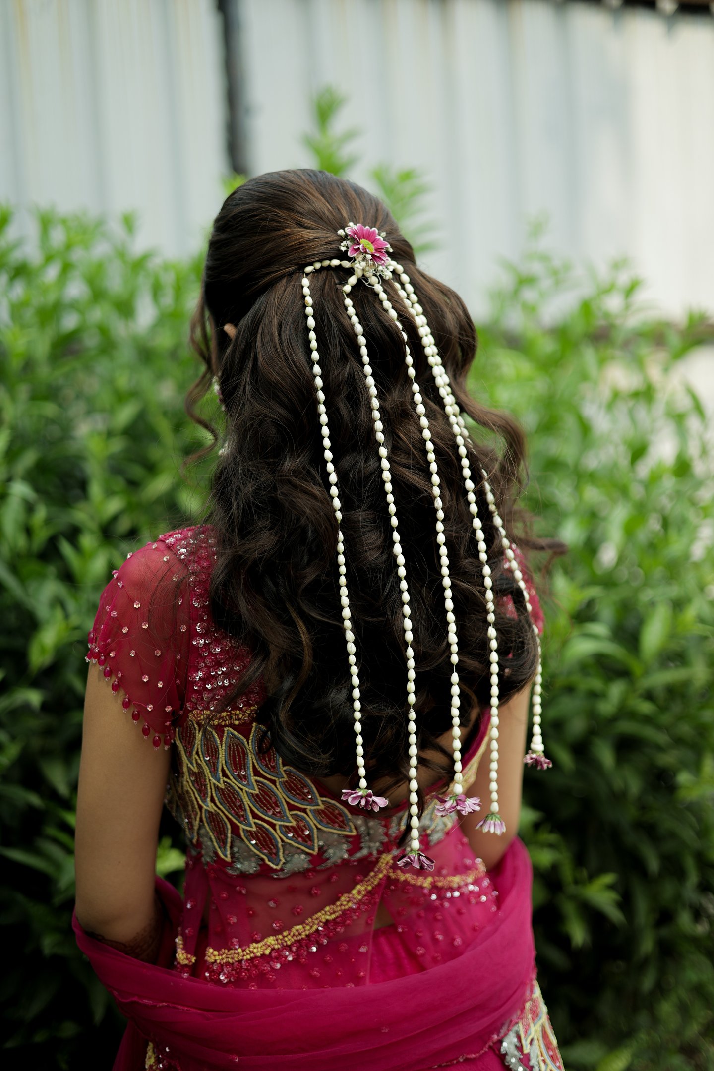 Open variation bridal hairstyle with white floral strings and pink flower clip by professional brida