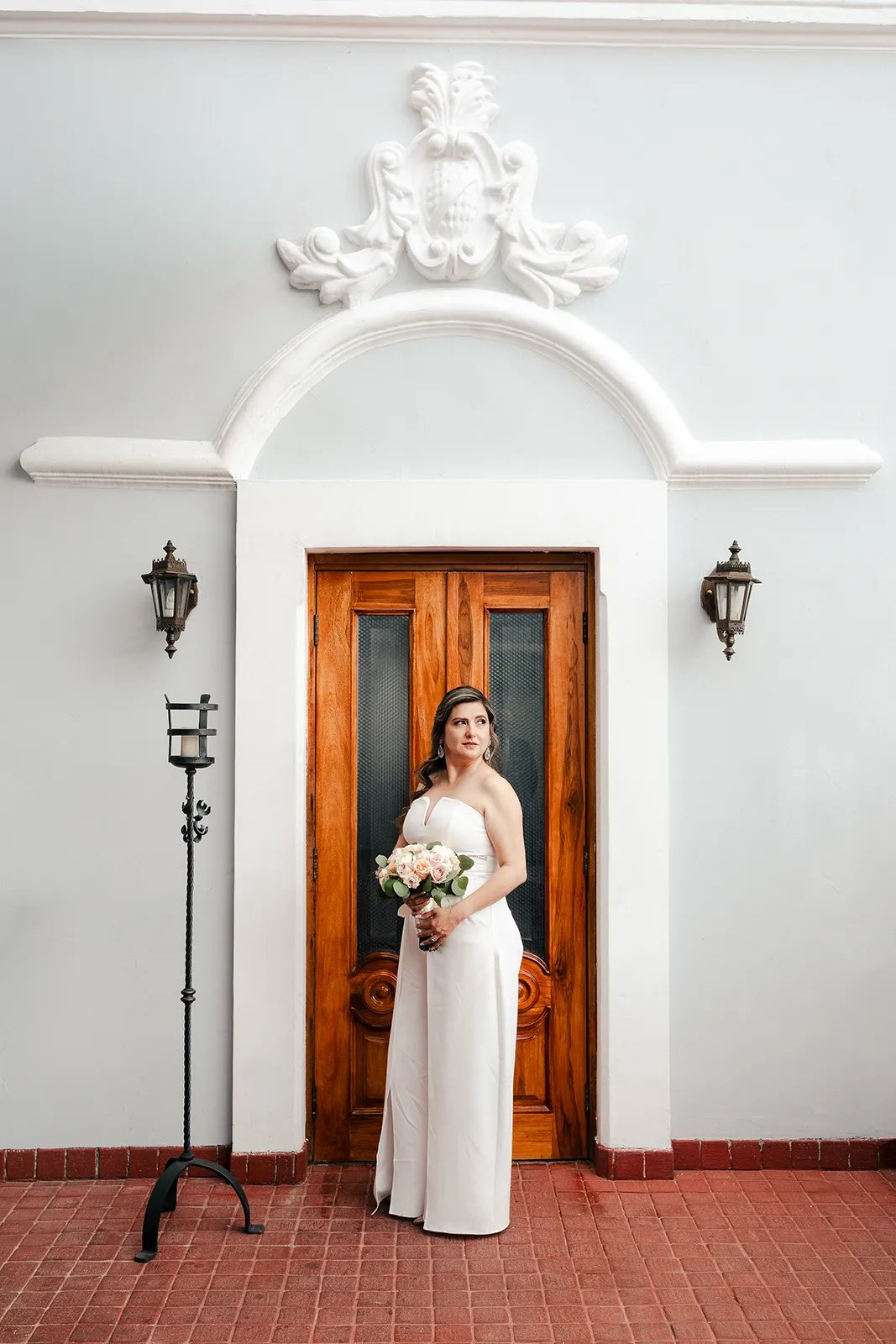 Novia en el día de su boda posando elegante con su ramo de flores en el centro histórico de Quito
