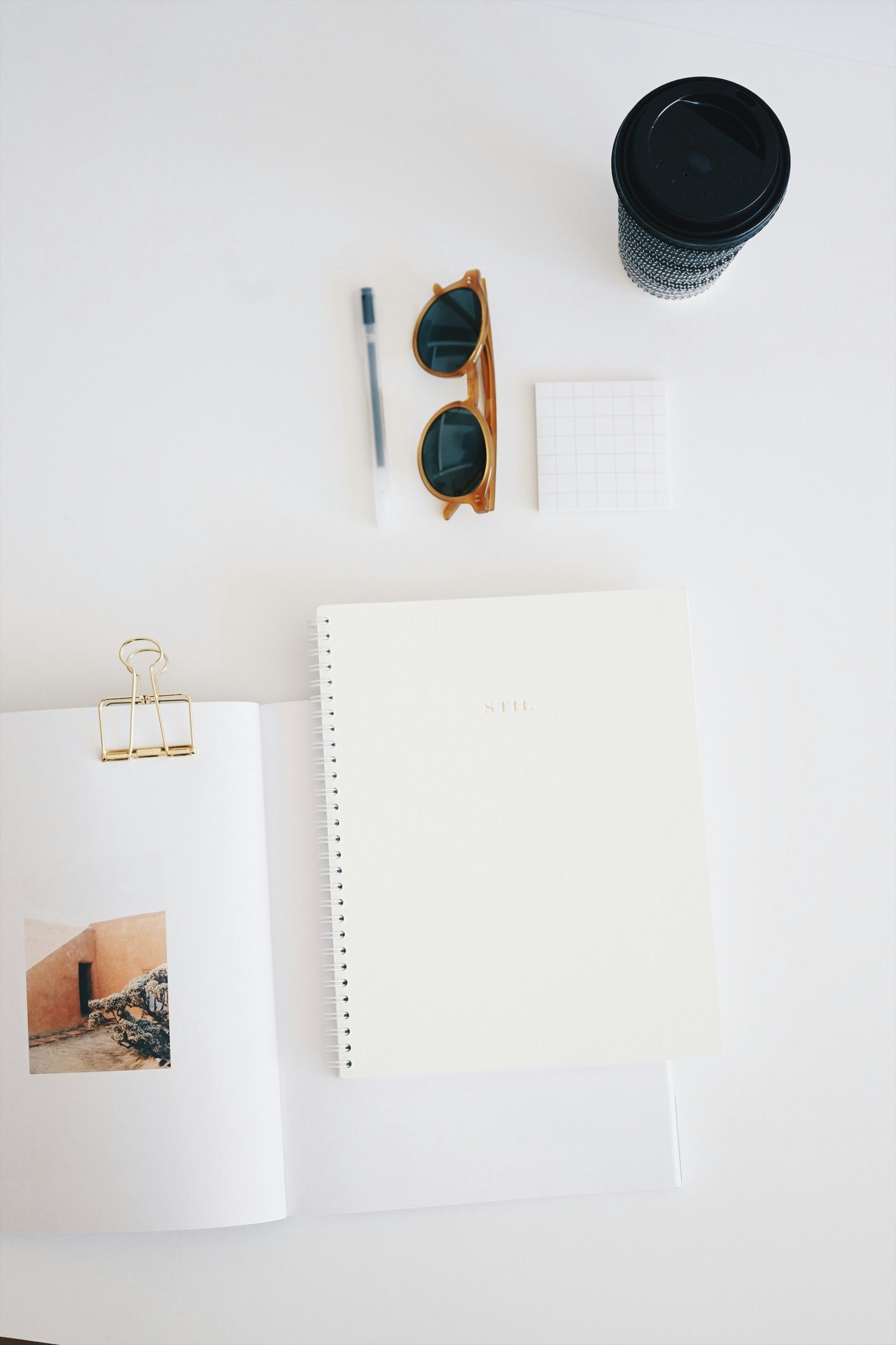 dessus de bureau blanc avec carnet, crayon, tasse de café. Un décor tout en simplicité
