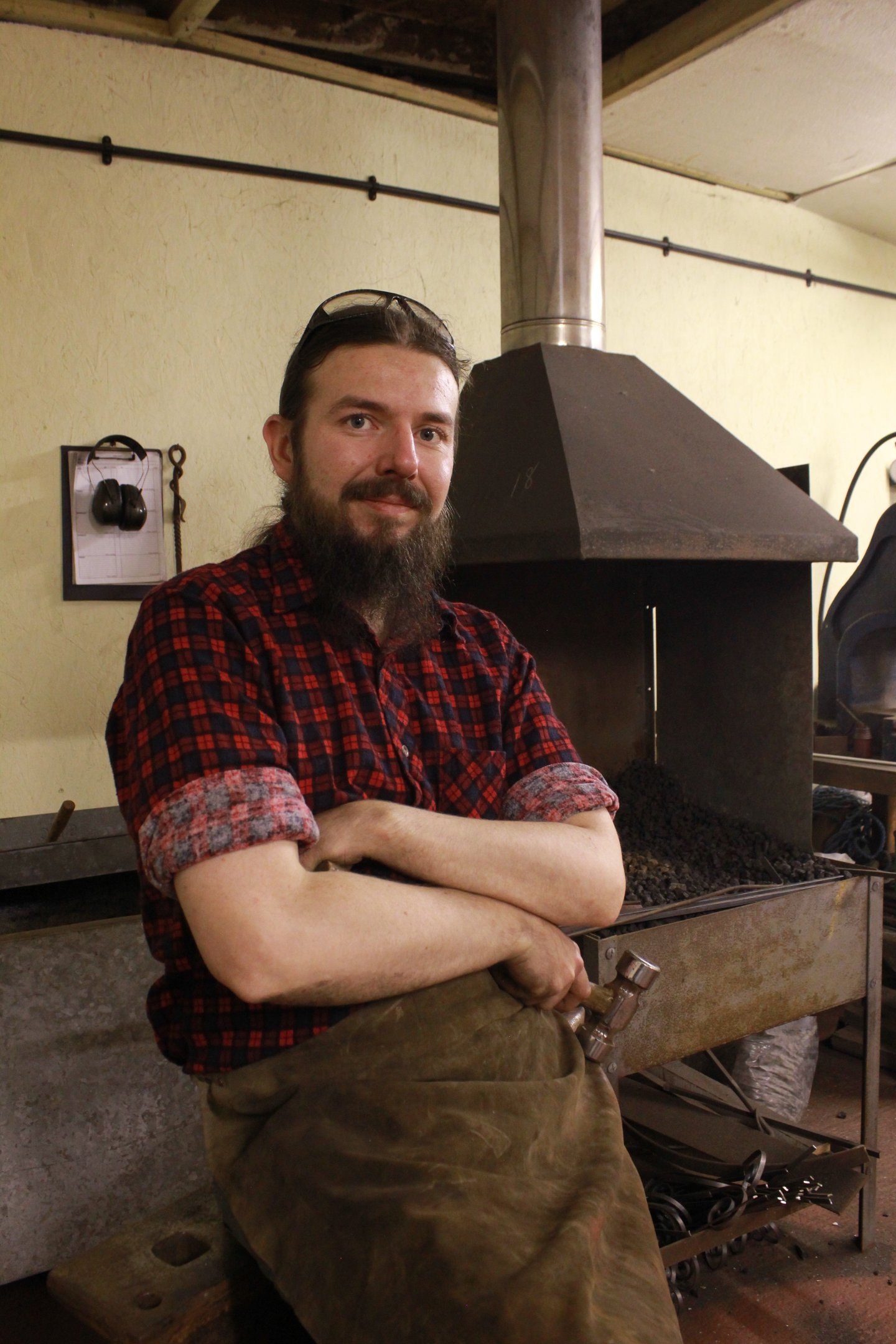 sexy bearded blacksmith with his arm crossed looking dahing in forge 