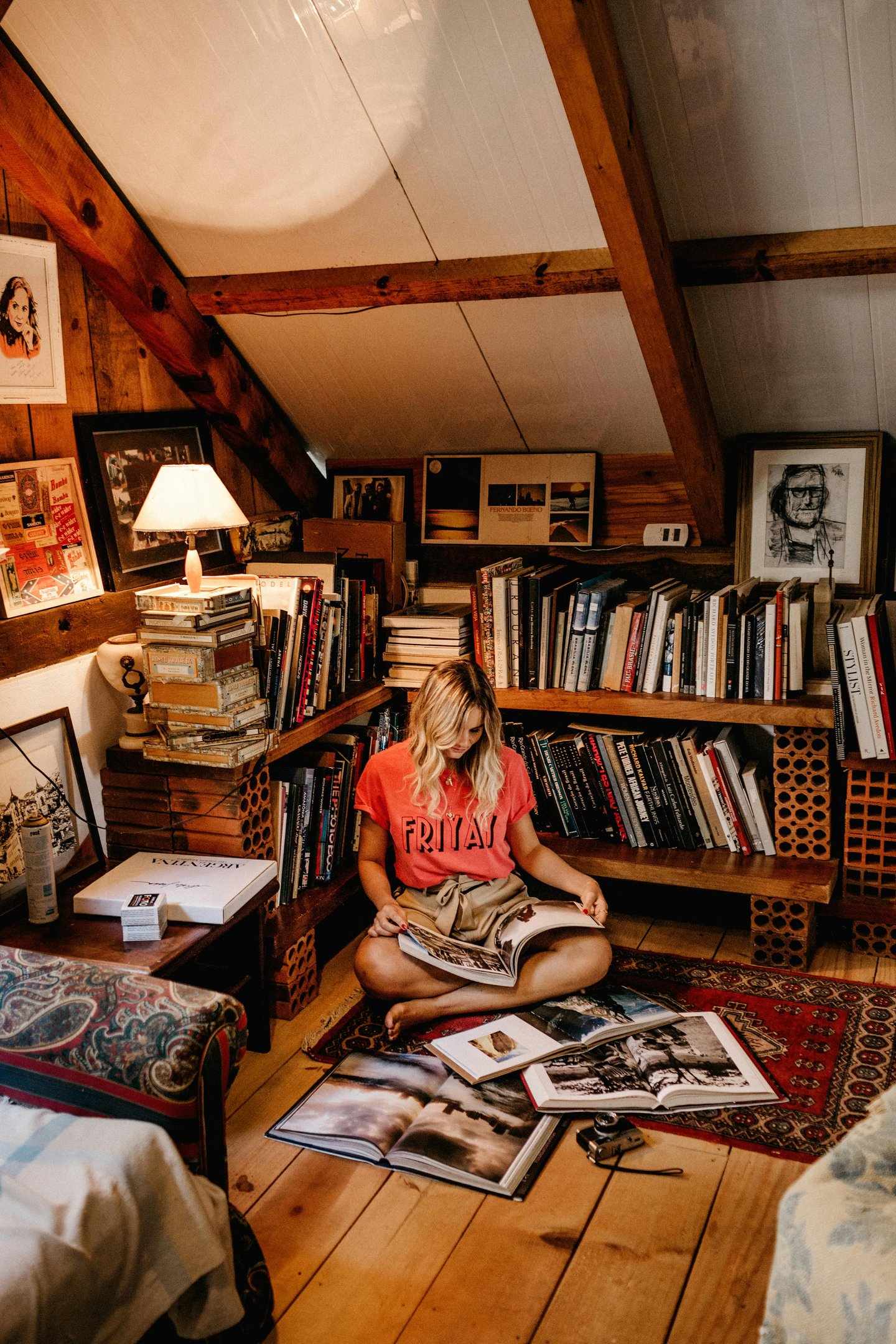 Young woman in attic, with bookshelves, reading a book
