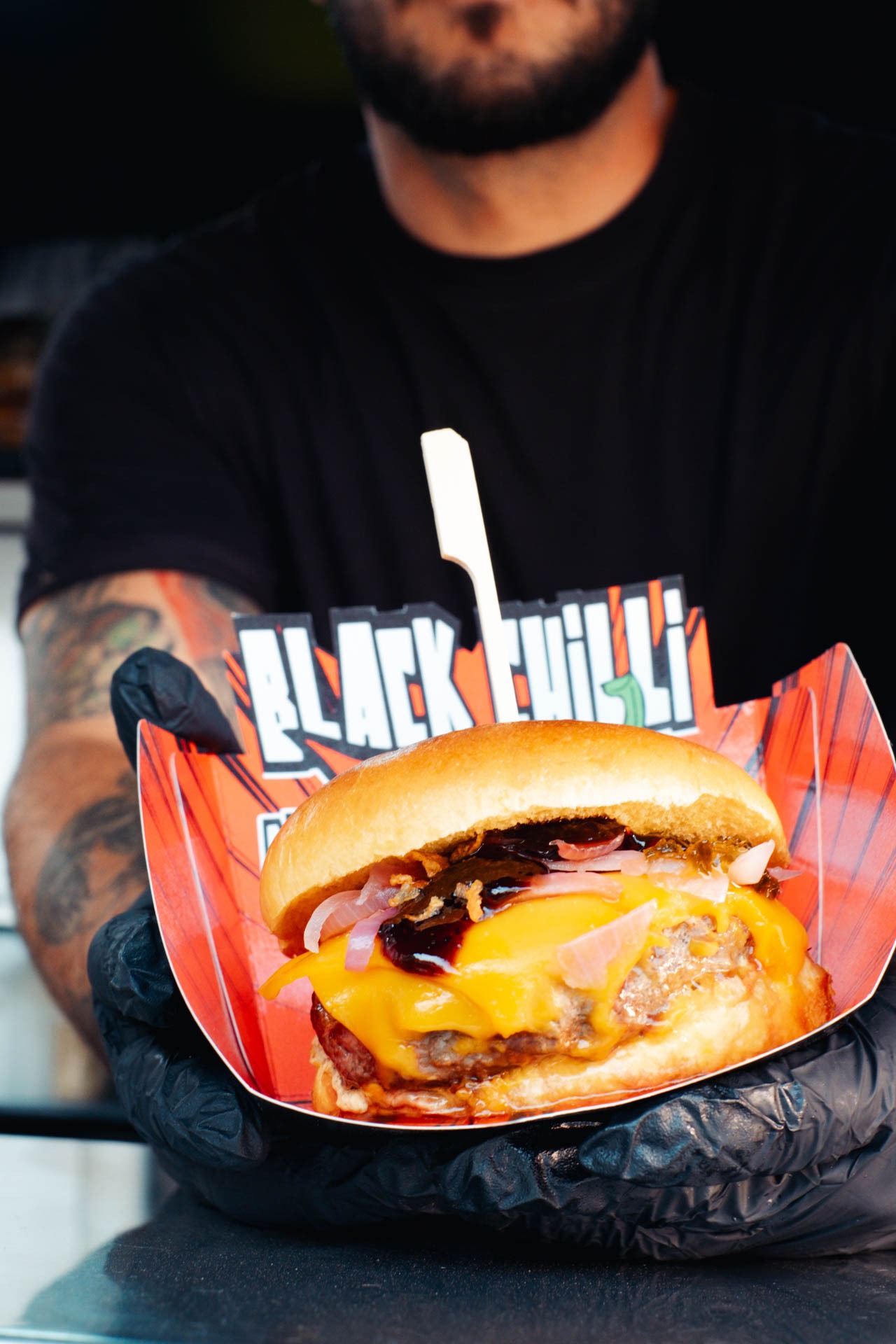 a man holding a large hamburger burger on a paper plate