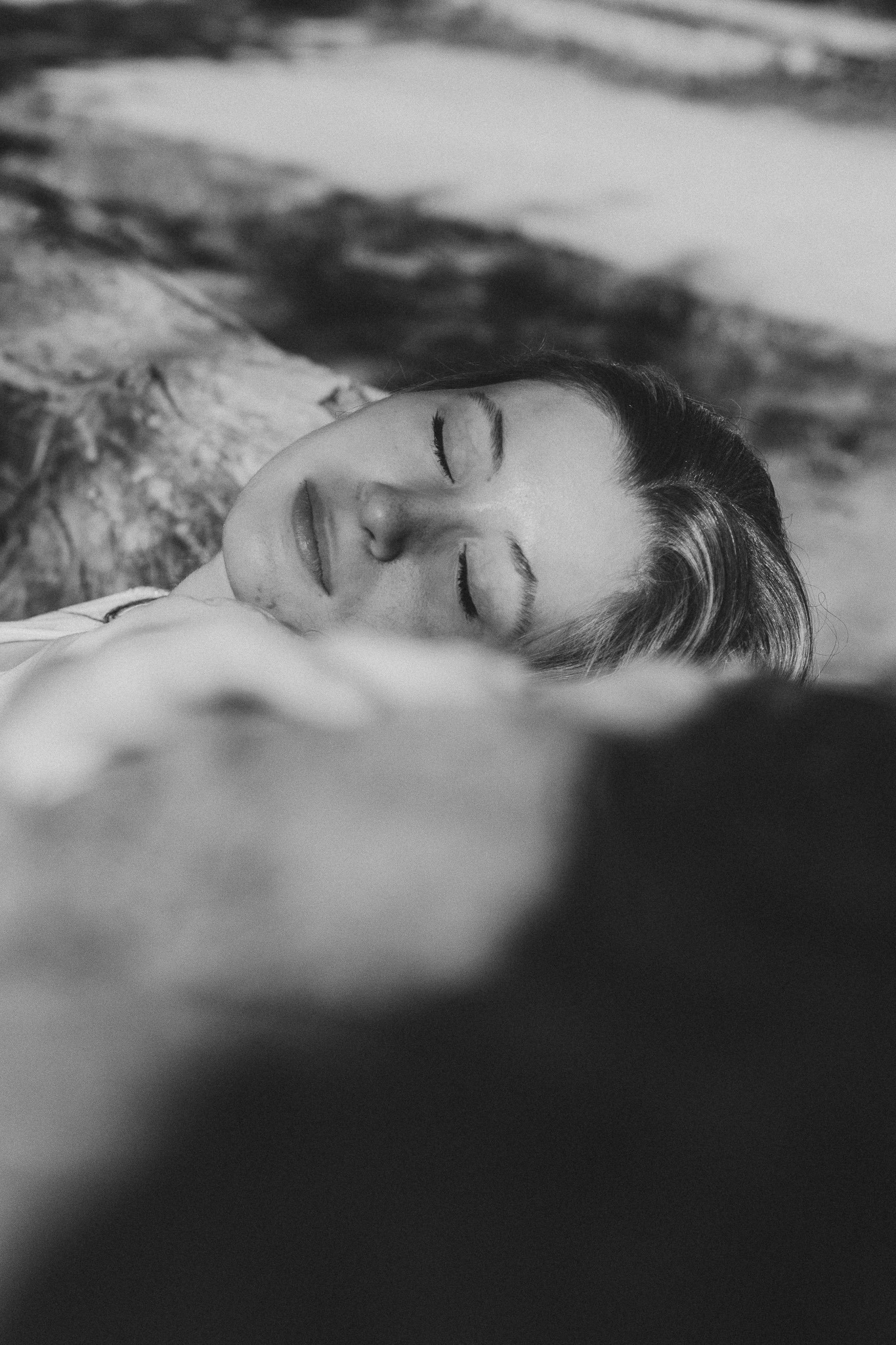 portrait féminin en noir et blanc yeux fermé allongé sur un tronc d'arbre 