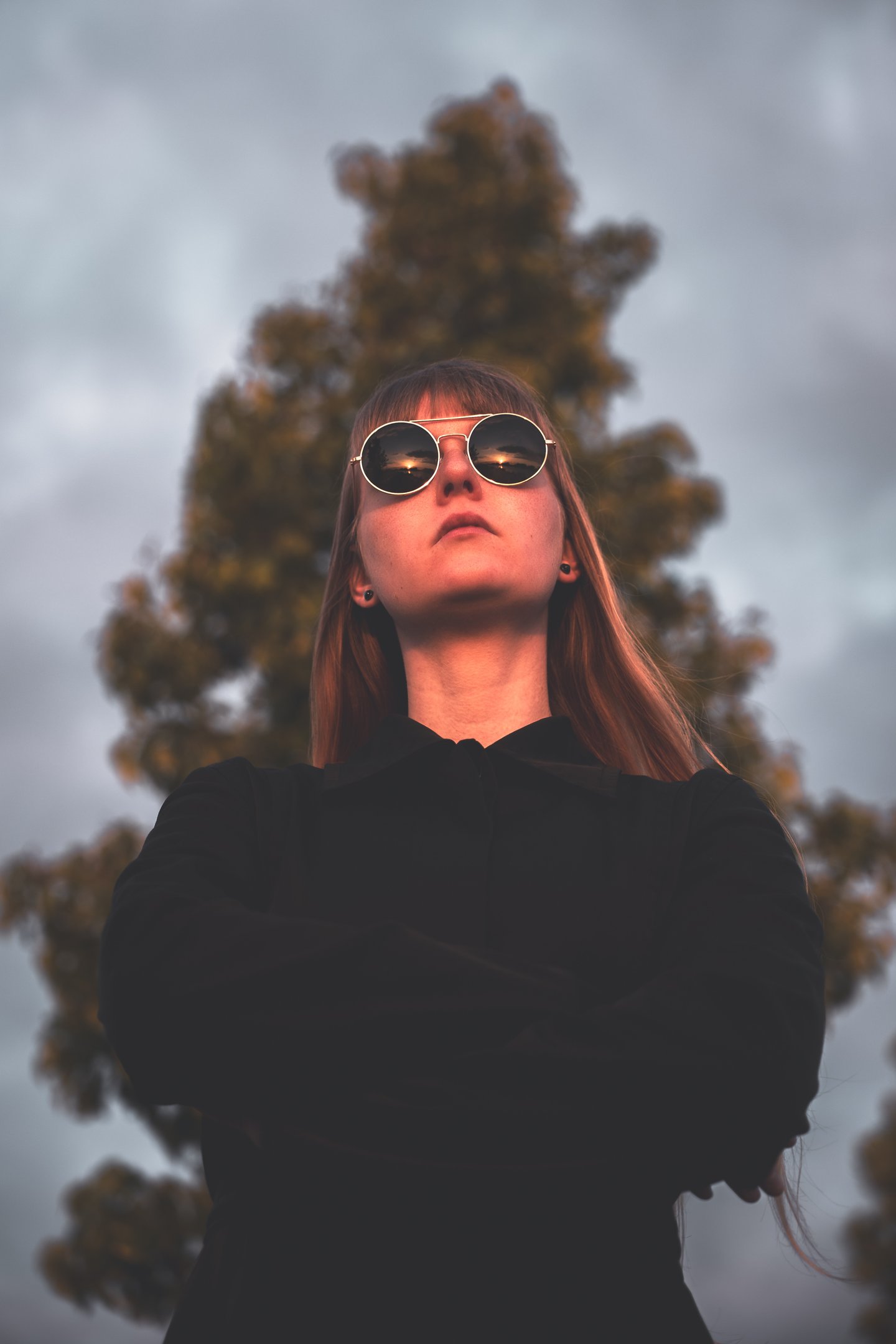 a women in a black jacket and sunglasses staring into the sunset